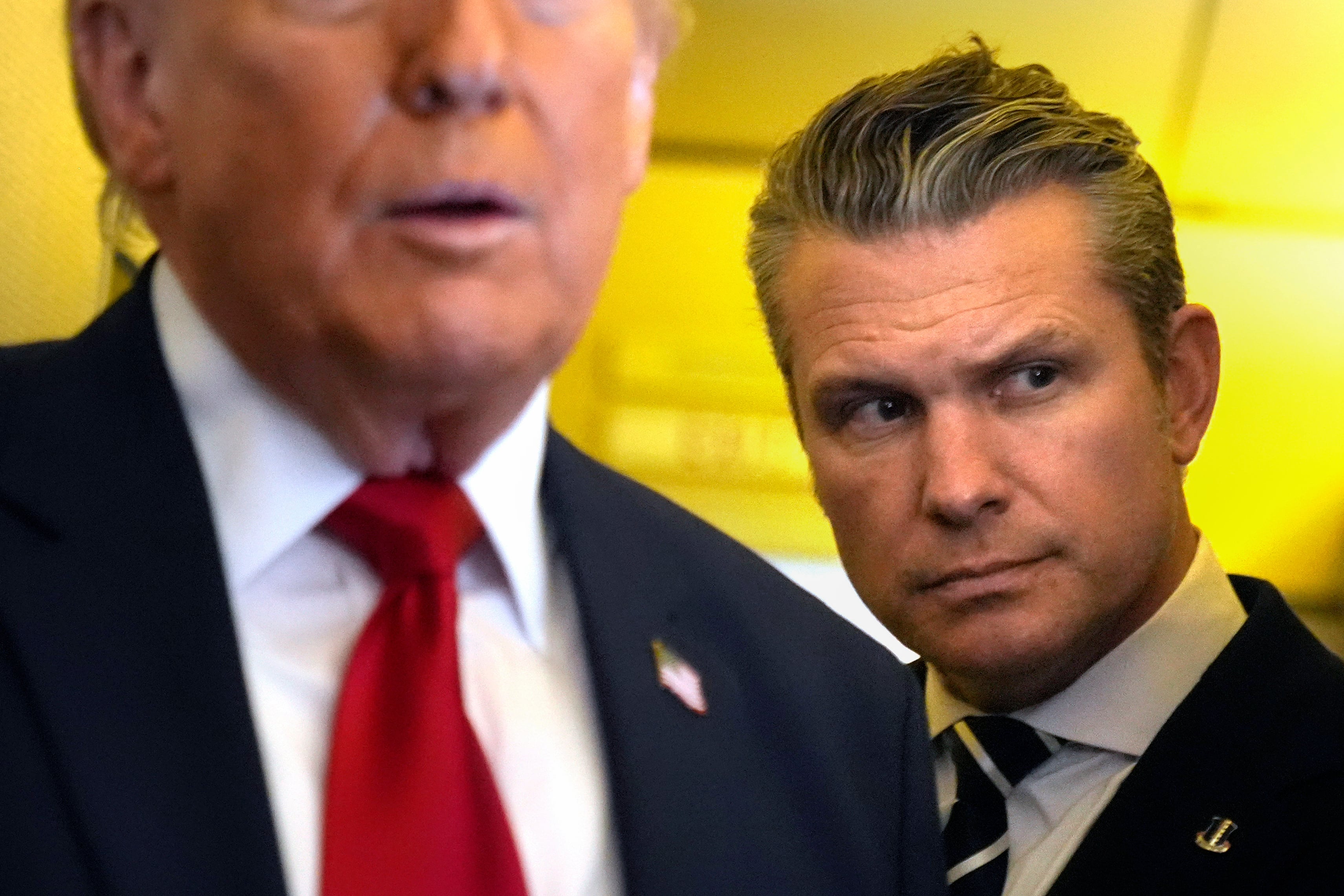 El secretario de Defensa de Estados Unidos, Pete Hegseth, escucha mientras el presidente Donald Trump habla con periodistas; buscan realizarles un juicio político (AP Foto/Mark Schiefelbein)