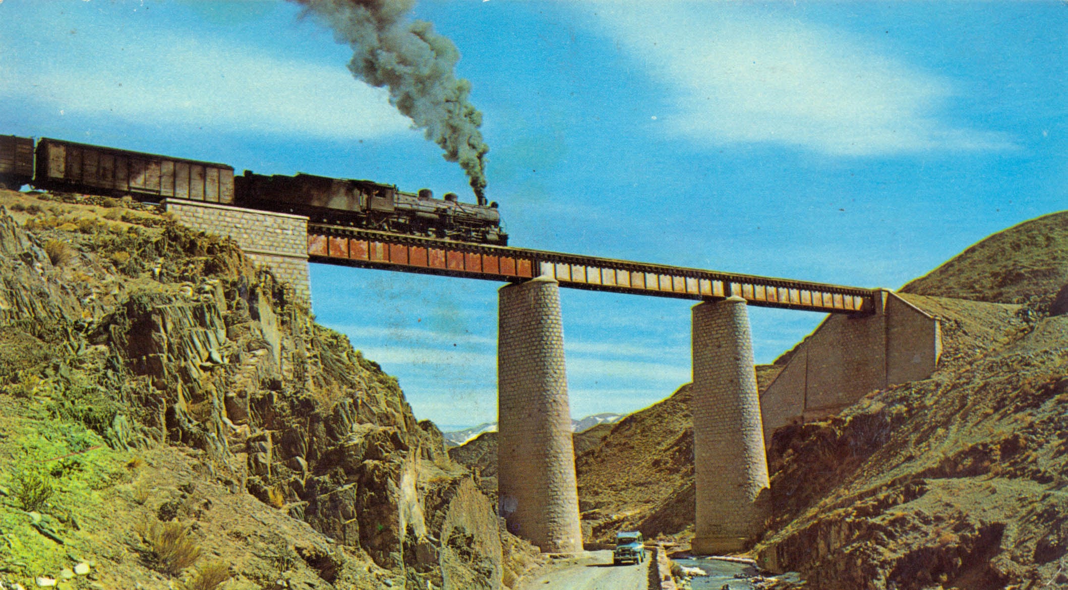 Cruce de tren con locomotora a vapor por el viejo trazado de la ruta pegada al encauzado río San Antonio (Colección Pezzimenti)