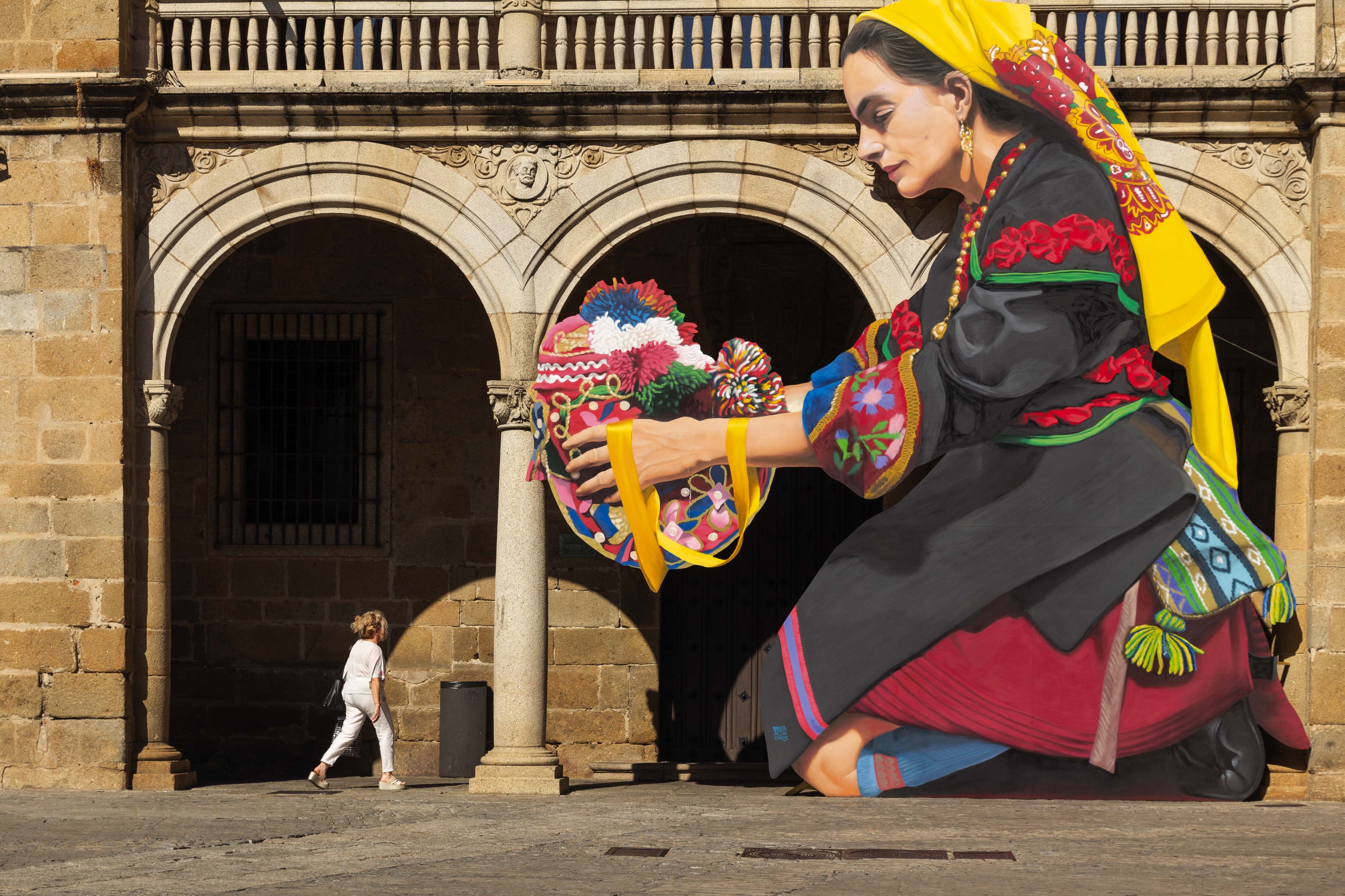Gigantografía de una mujer montehermoseña con traje típico y gorra bordada, en la Plaza Mayor de Plasencia