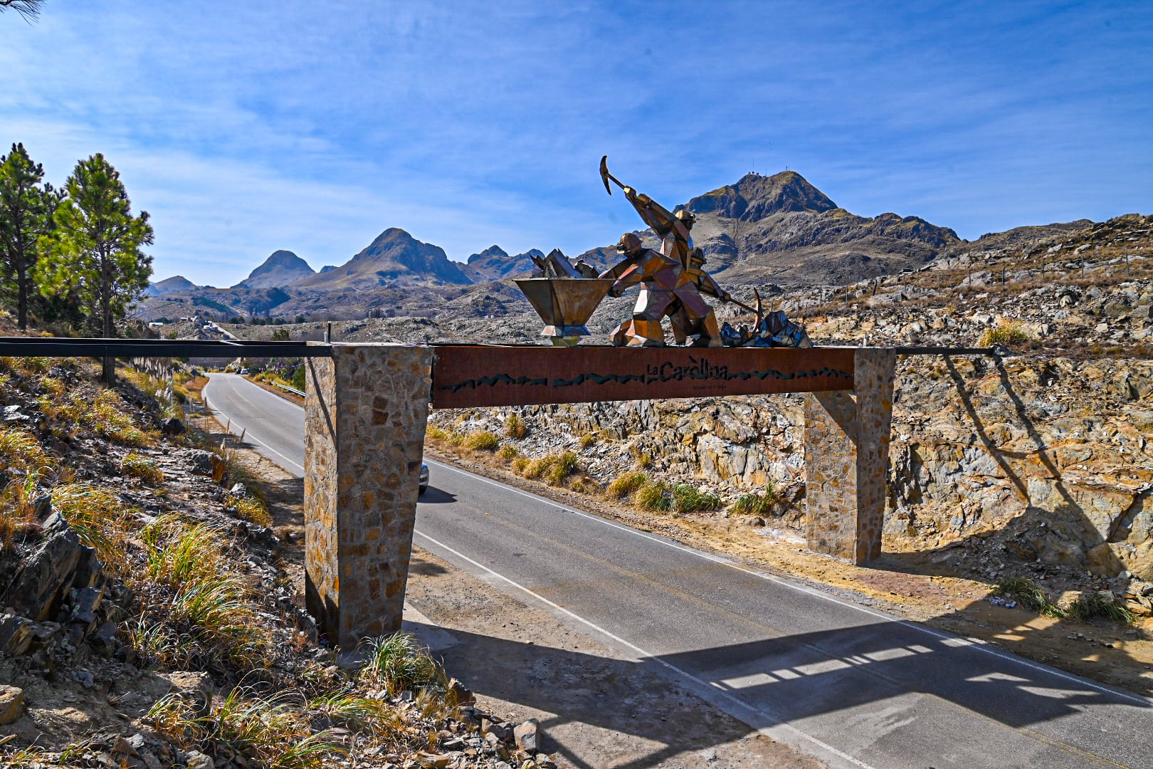 El acceso rutero al pueblo, con homenaje a los mineros extrayendo el oro