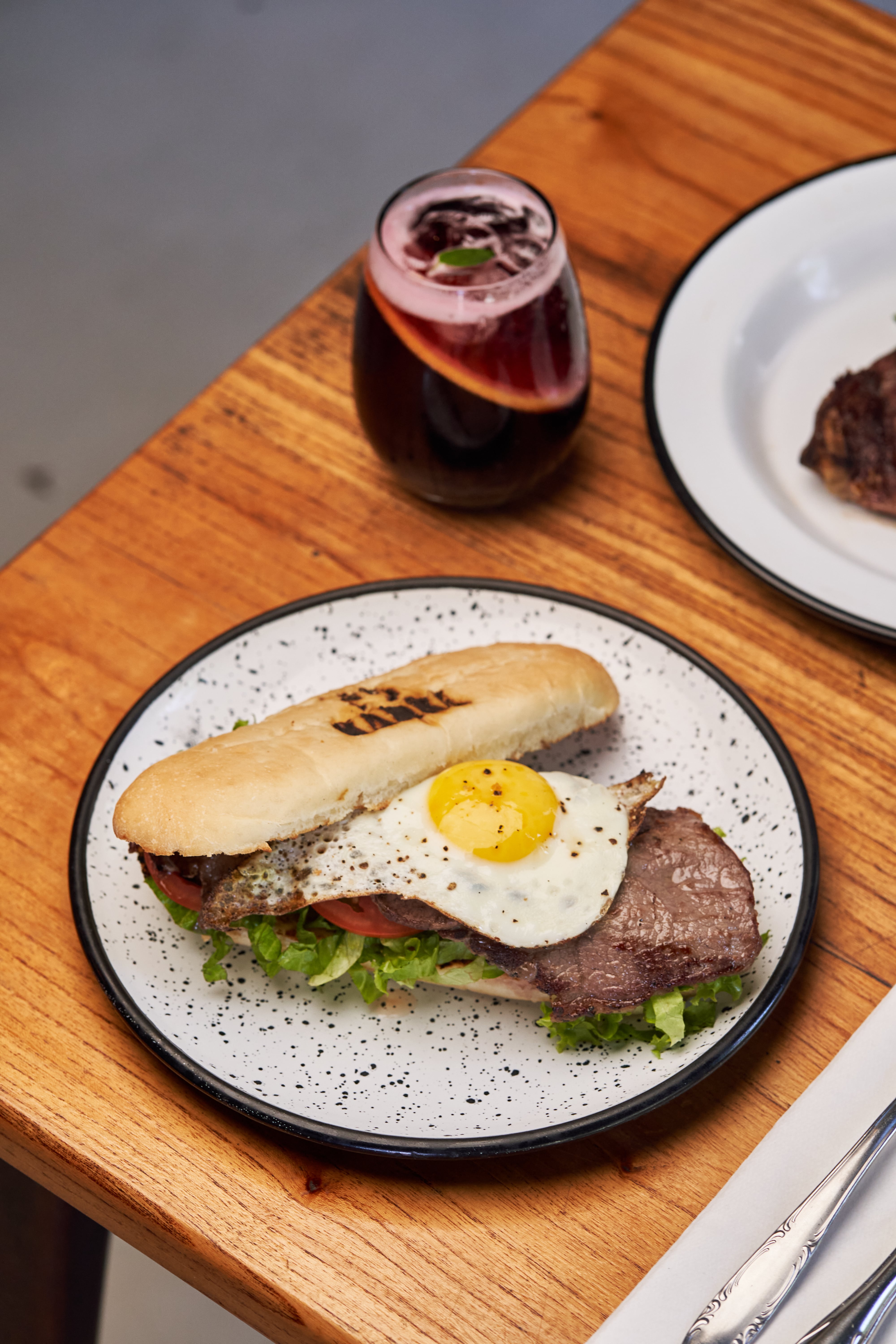 Sándwich de lomito con huevo, lechuga, tomate, morrón asado y alioli