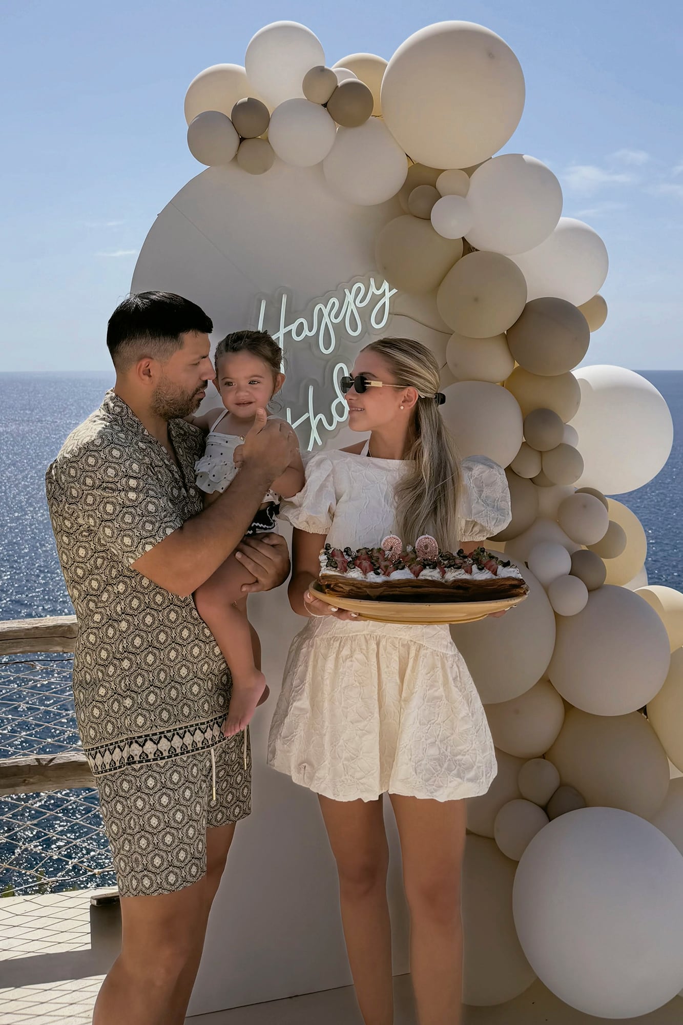 ¡Happy birthday! La cumpleañera, con un vestido de estilo romántico off white. La escoltan su hija Olivia y su amor, Sergio “Kun” Agüero, lookeado con un conjunto de camisa y pantalón corto