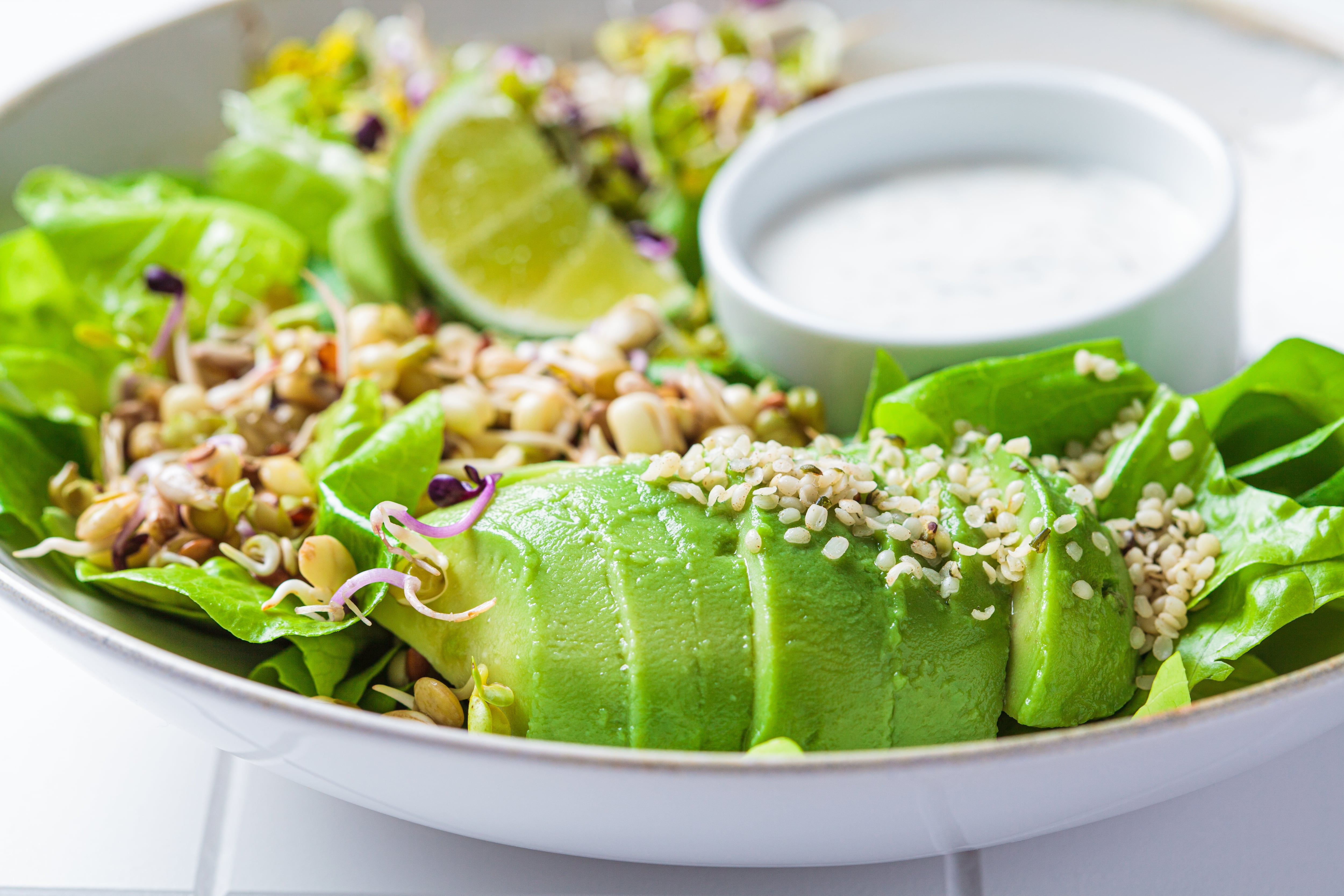 Ensalada detox verde con palta, brotes, semillas de cáñamo y yogur aderezado.