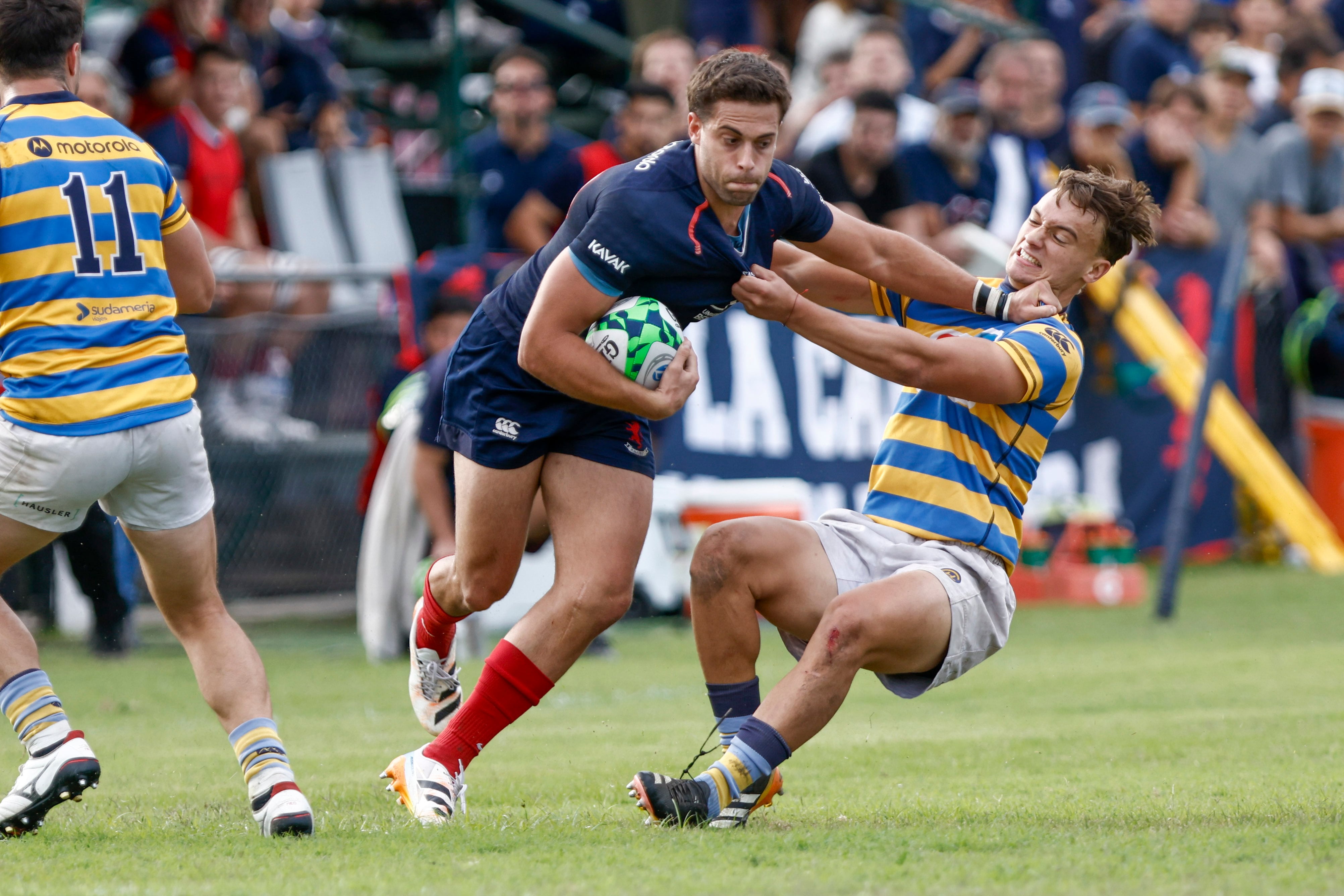 Ramiro Costa se saca de encima a Ramón Fernández Miranda con un hand-off, ante Federico Graglia; Buenos Aires contribuyó al desarrollo de un partido alocado en su cancha y, pese a la derrota por 22 tantos, fue fervoroso en su juego.