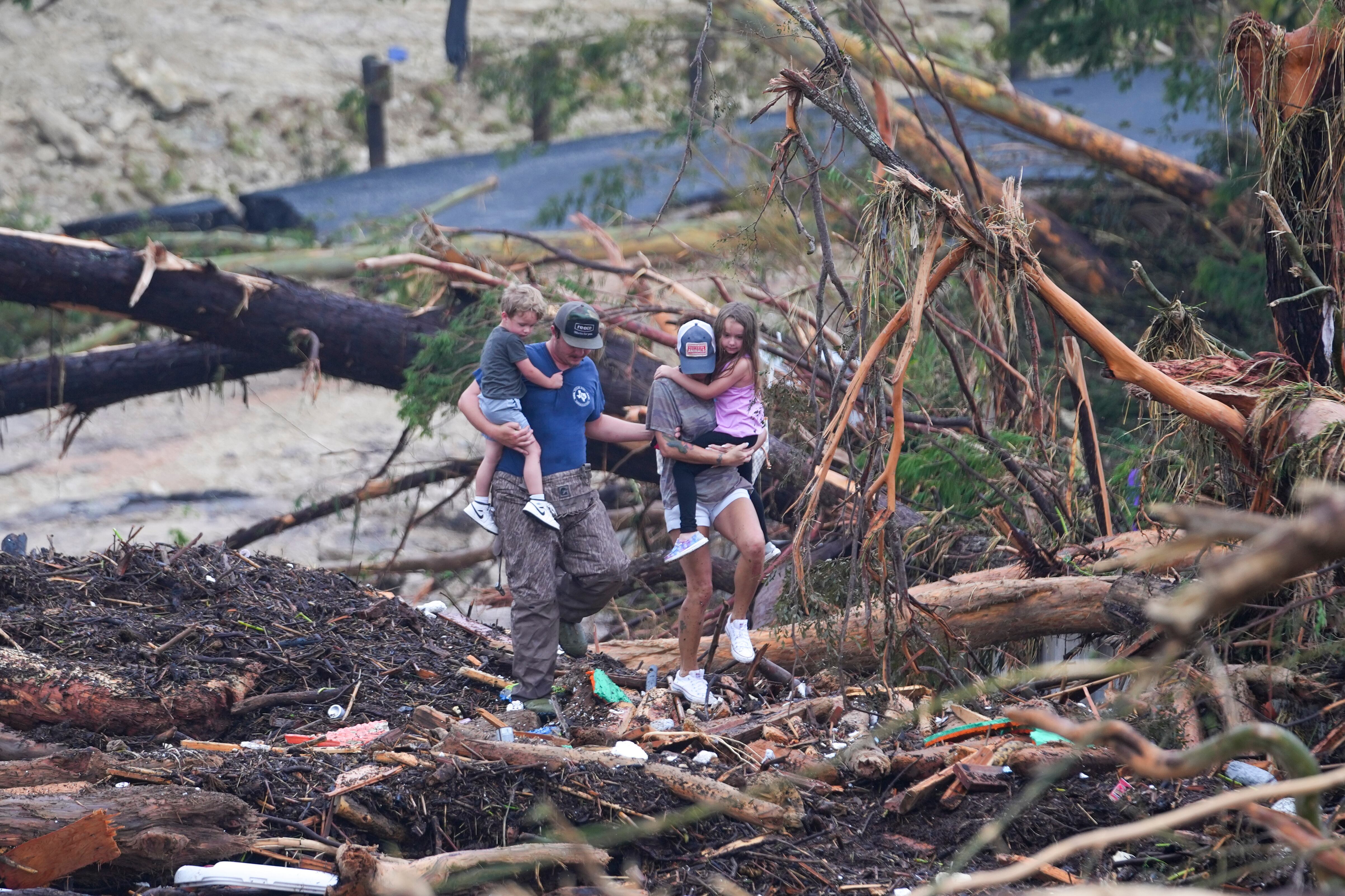 Varias personas trepan por los restos de un puente sobre el río Guadalupe después de que una inundación repentina arrasara el área, el sábado 5 de julio de 2025, en Ingram, Texas. (AP Foto/Julio Cortez)