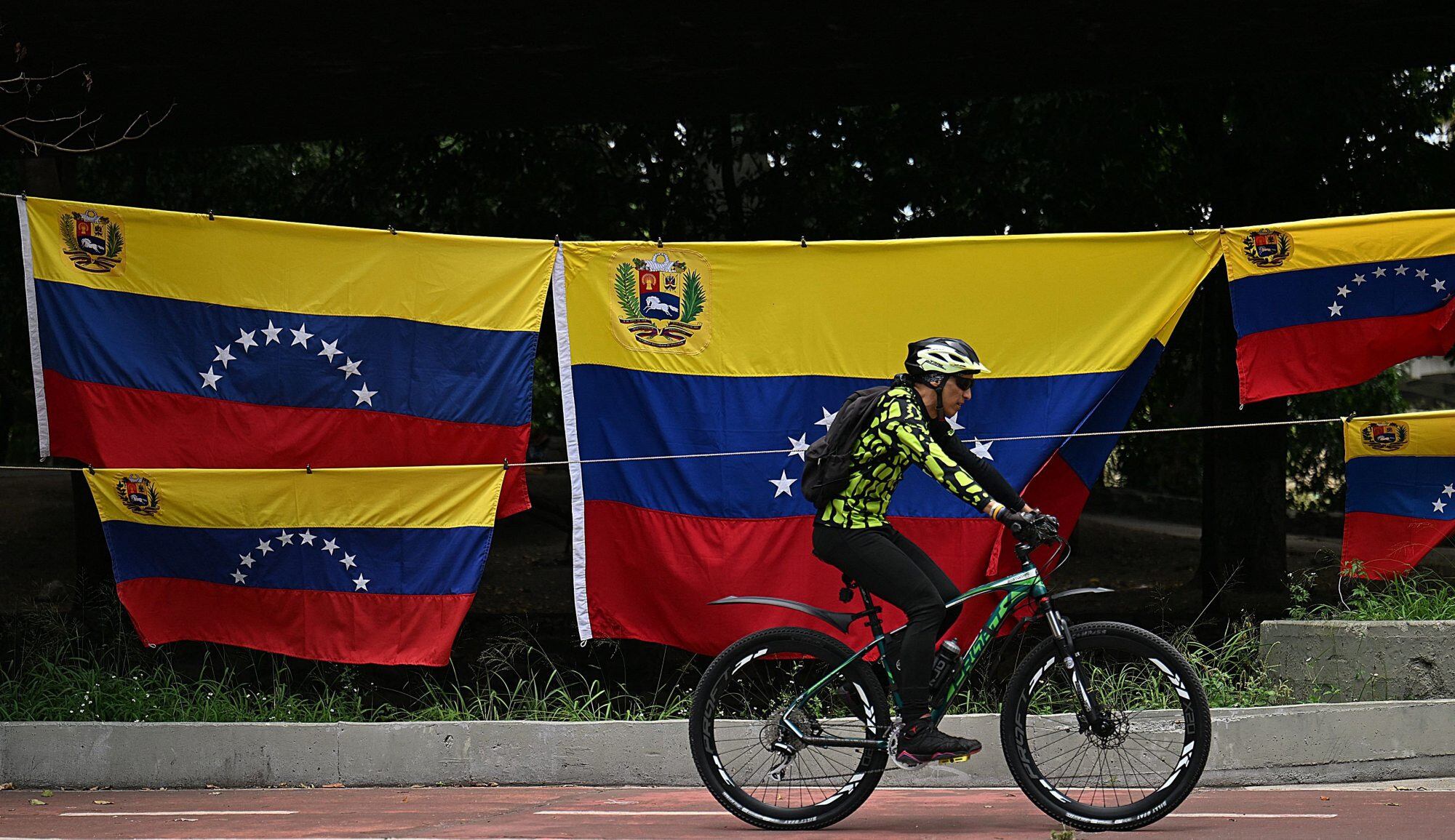 A cyclist rides past Venezuela's flags for sale in Caracas on September 15, 2025. Venezuela's President Nicolas Maduro on Monday vowed his country would defend itself from what he called US