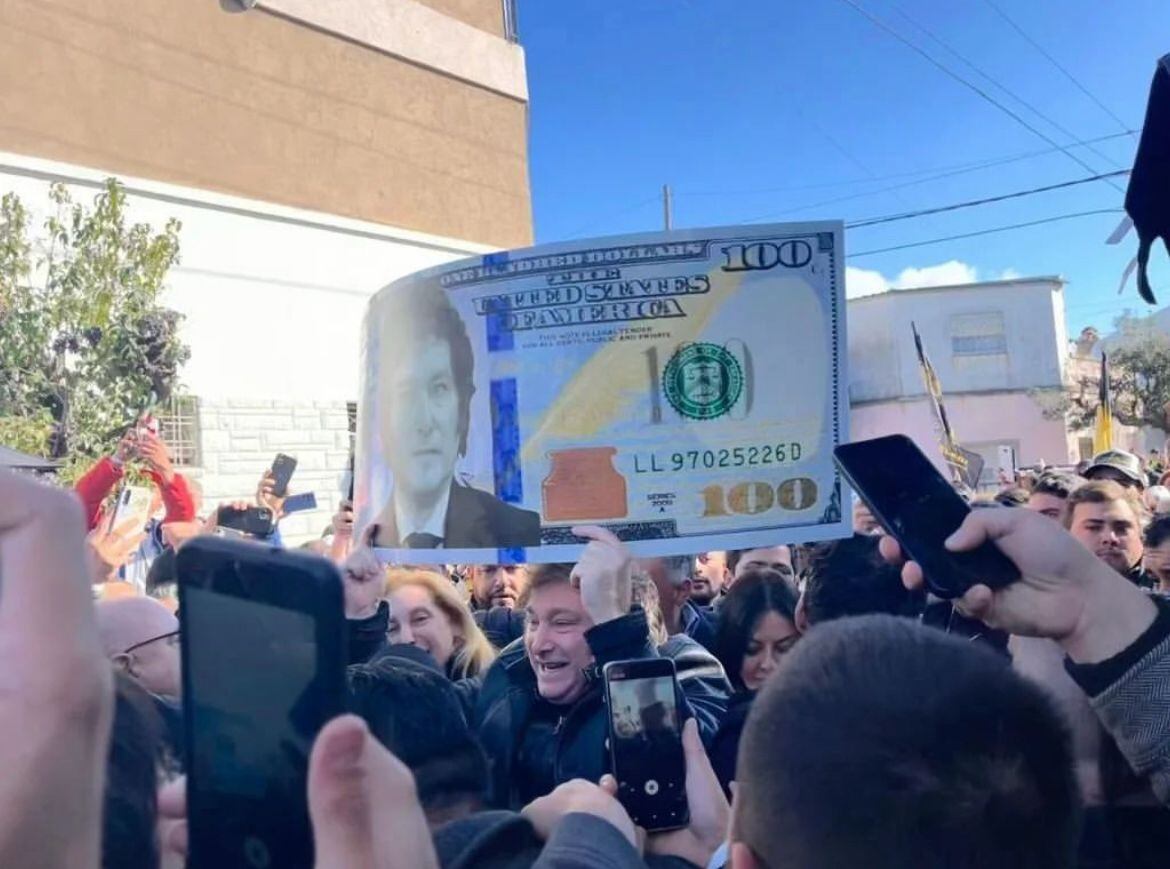 Javier Milei en plena campaña electoral junto a un billete de dólar con su cara.