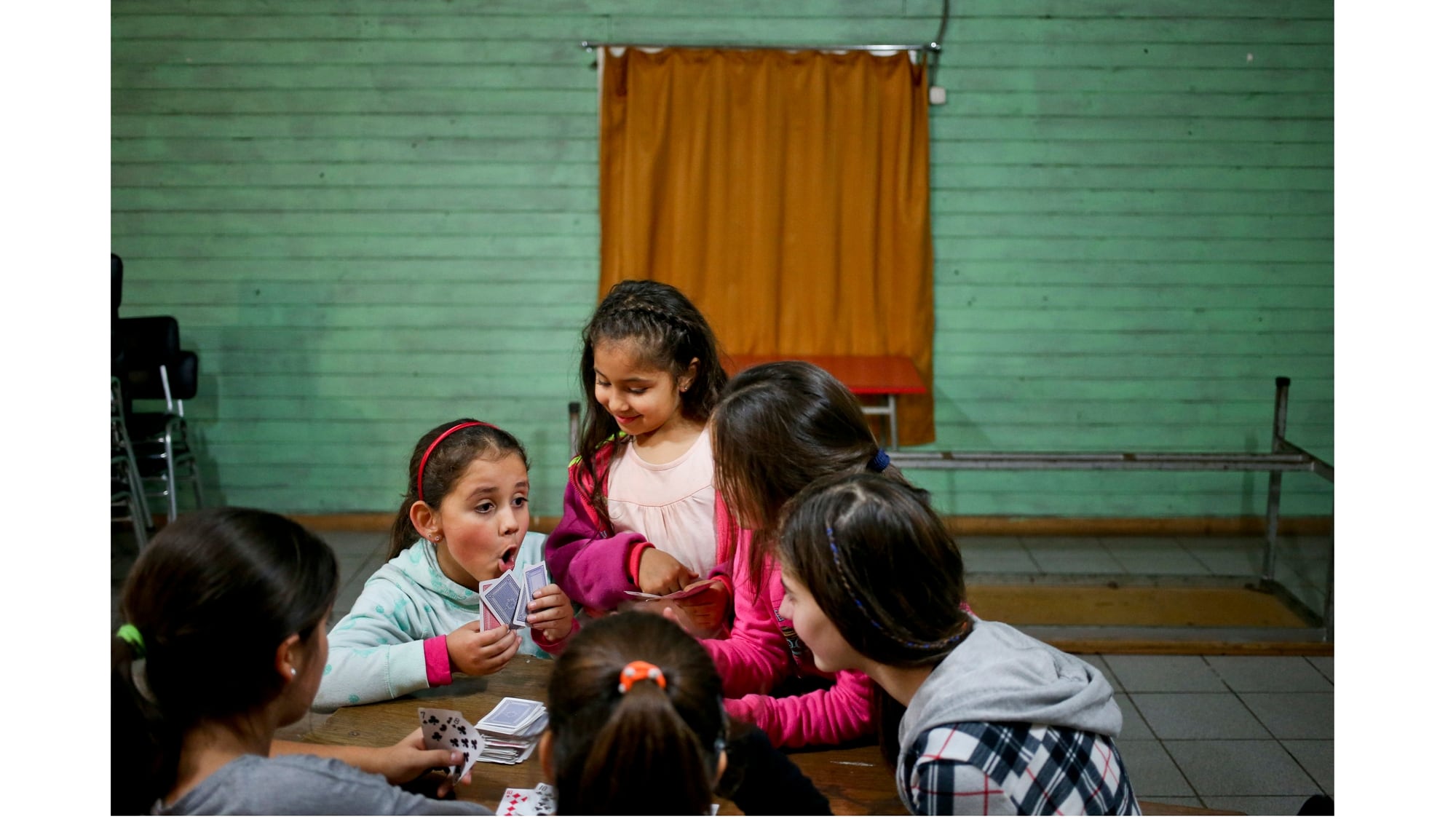 Selenna, izquierda, juega cartas durante un descanso con otras chicas durante una clase de baile en su centro comunitario en Santiago de Chile
