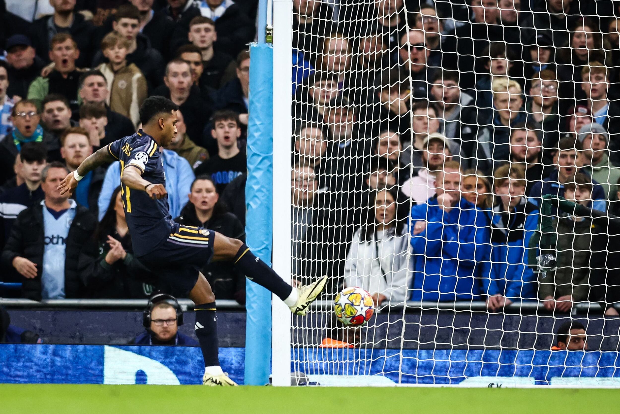 Real Madrid's Brazilian forward #11 Rodrygo (L) shoots the ball and scores his team first goal during the UEFA Champions League quarter-final second-leg football match between Manchester City and Real Madrid, at the Etihad Stadium, in Manchester, north-west England, on April 17, 2024. (Photo by Darren Staples / AFP)