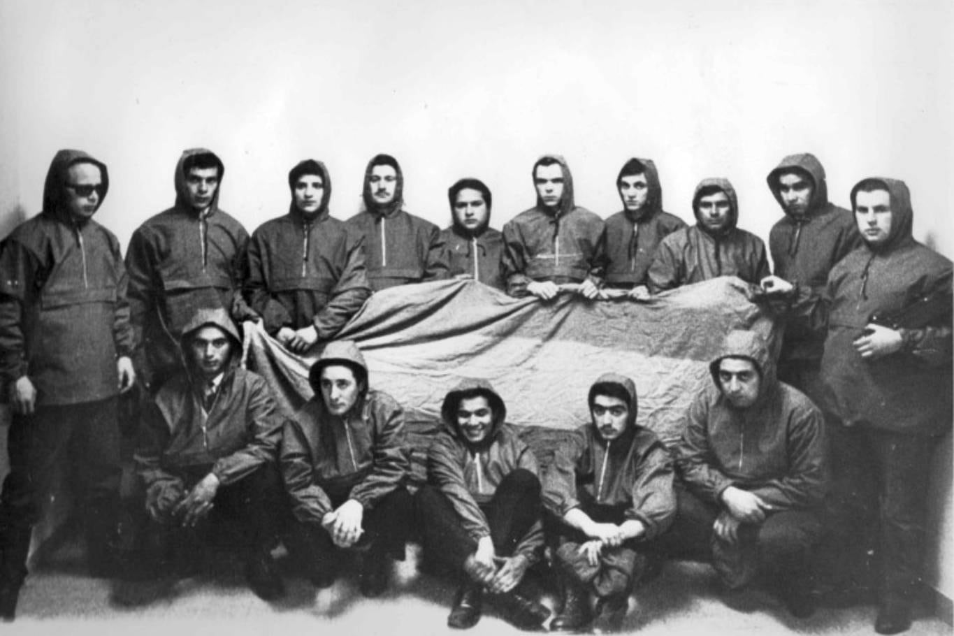 15 de los 18 protagonistas del Operativo Cóndor junto a una de las banderas que colgaron en las Islas Malvinas