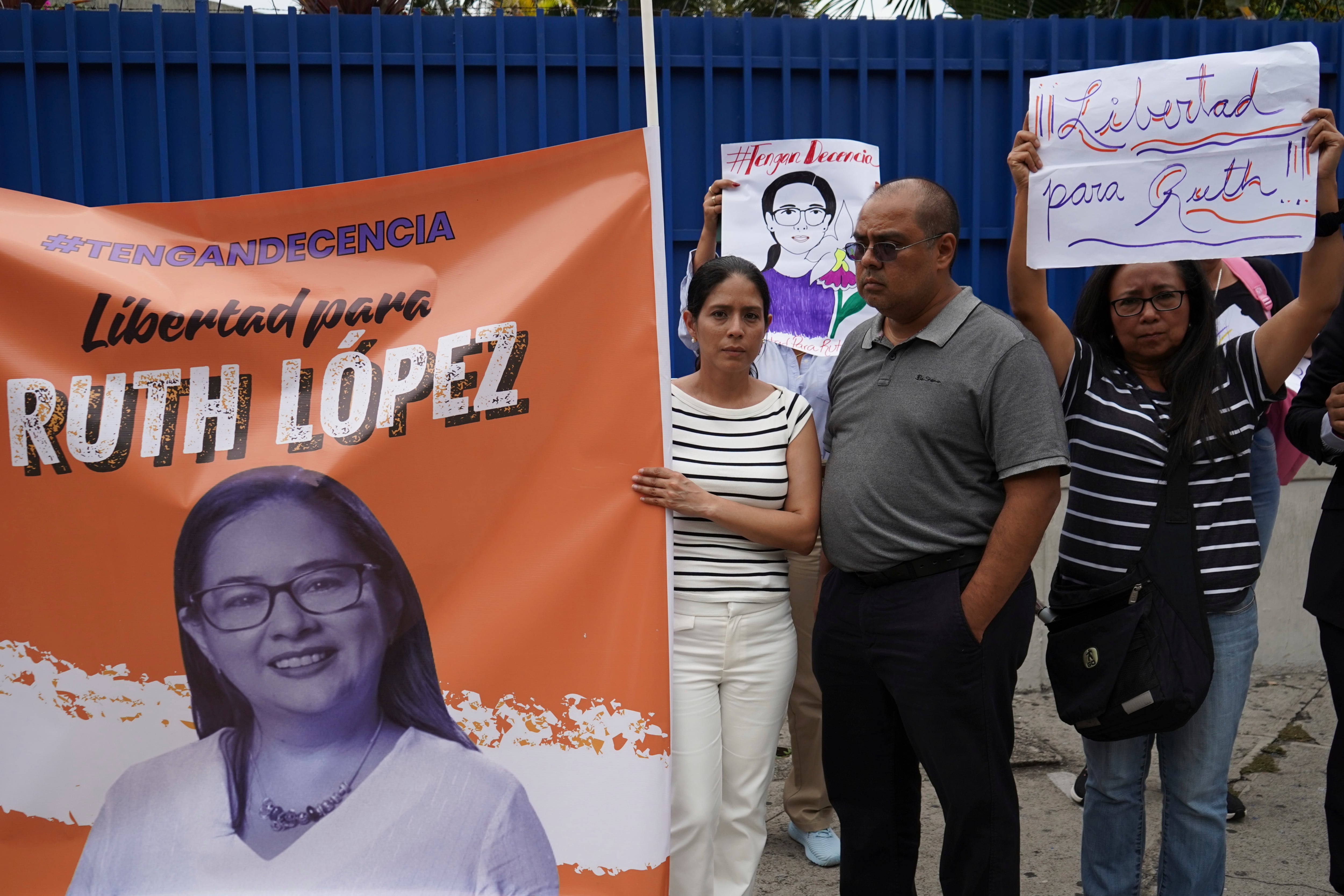 Seguidores de la abogada de derechos humanos Ruth López, detenida en El Salvador, con un cartel de respaldo a las afueras de los tribunales en San Salvador, el miércoles 4 de junio de 2025, el día en que un juez debía decidir si aceptaba los cargos formulados por la fiscalía contra ella por enriquecimiento ilícito. (AP Foto/Salvador Meléndez)
