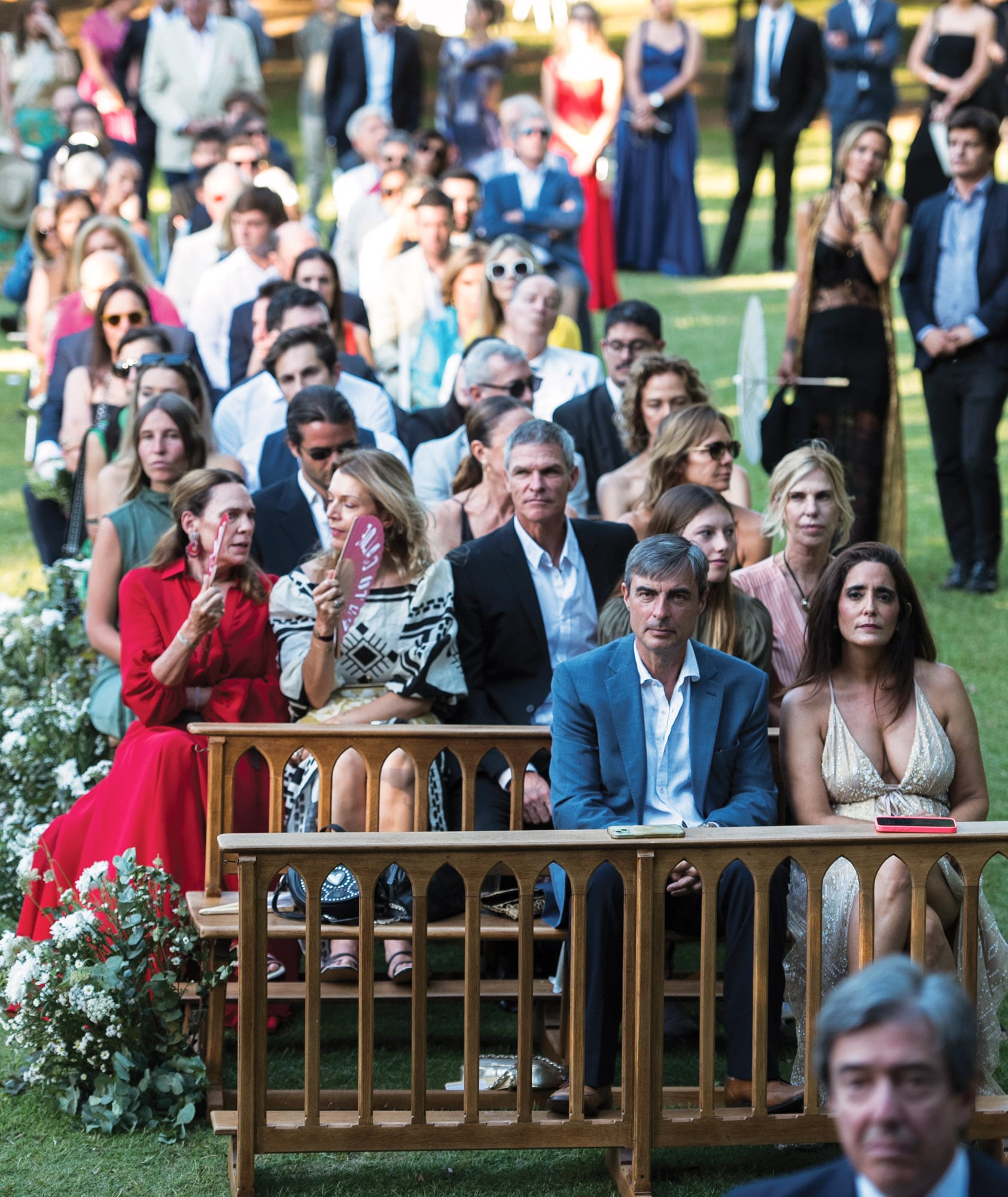 Los invitados a los que se les repartieron abanicos y
parasoles se ubicaron en bancos decorados con flores
blancas, dispuestos a lo largo de la alfombra roja que
recorría el jardín.