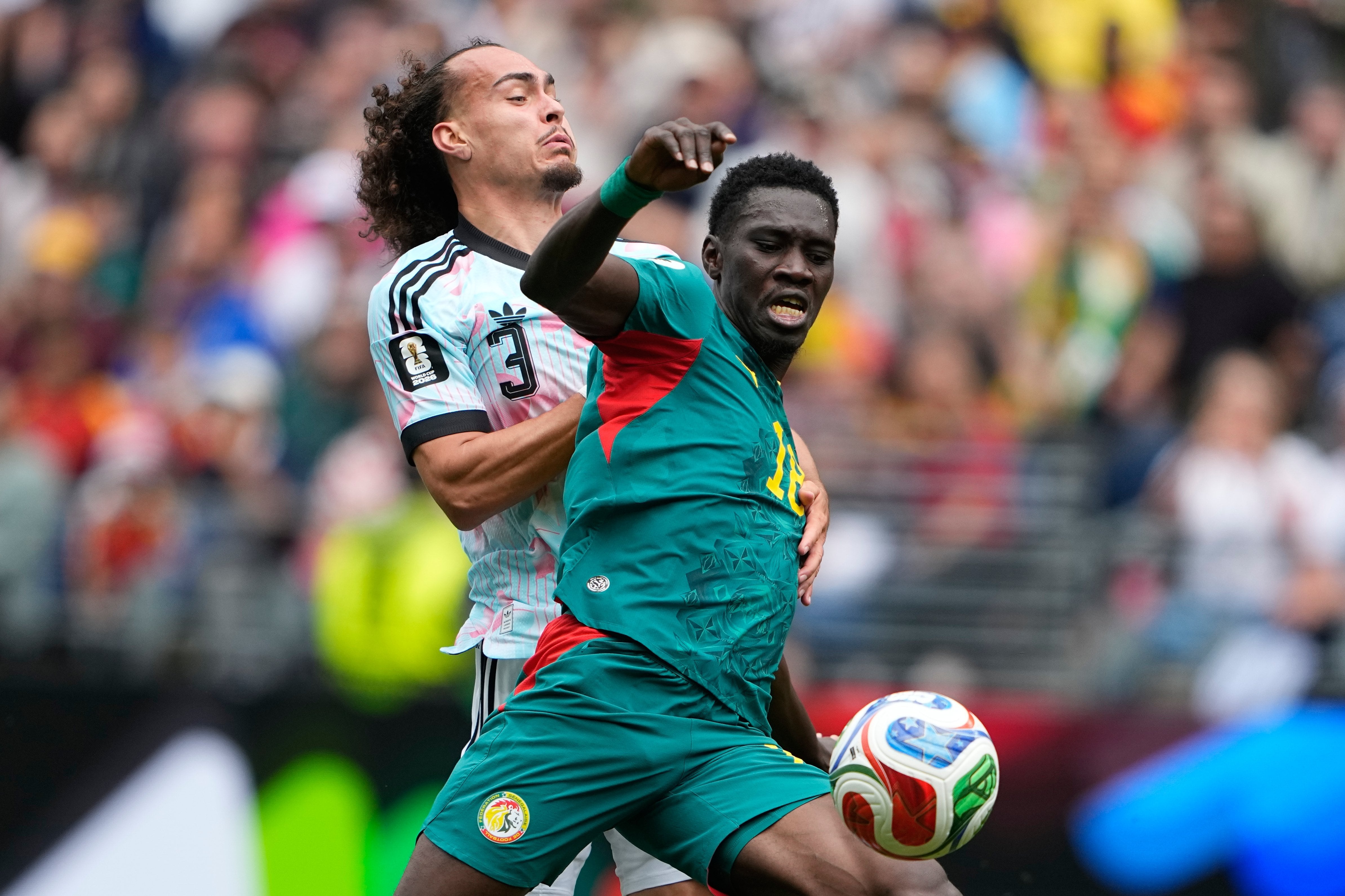 Ismaila Sarr cubre la pelota ante Theate para rematar