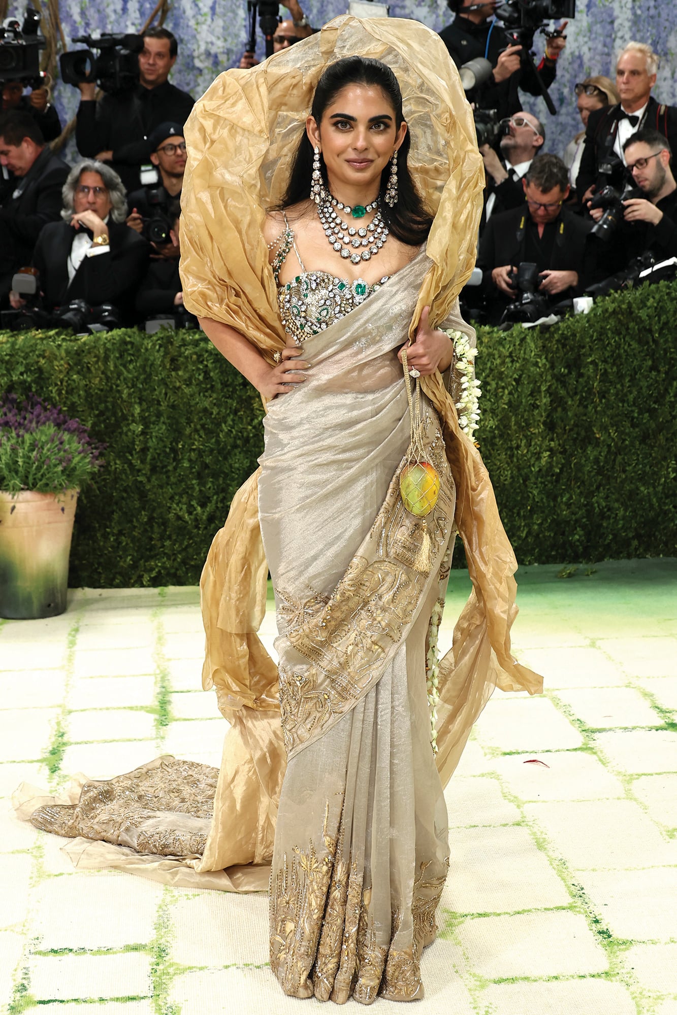 En la gala del MET, Isha brilló con un sari en tejido
de oro puro (con la firma de Gaurav Gupta) y un
deslumbrante conjunto de alta joyería. El soutien
tenía cosidos más de 1800 quilates de diamantes,
esmeraldas, piedras polki y kundan, procedentes de
la colección privada de su madre, Nita Ambani, de
valor incalculable. . Completó el outfit con una cartera
“mango”, una escultura de Subodh Gupta, cuyo
valor es de 100 mil dólares.