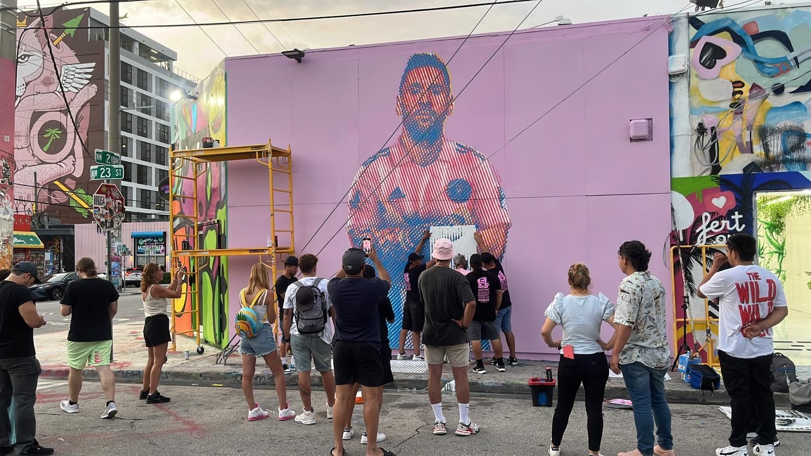 Arlex lleva a cabo su arte, la gente que pasea por el distrito de Wynwood, donde está el mural, lo mira
