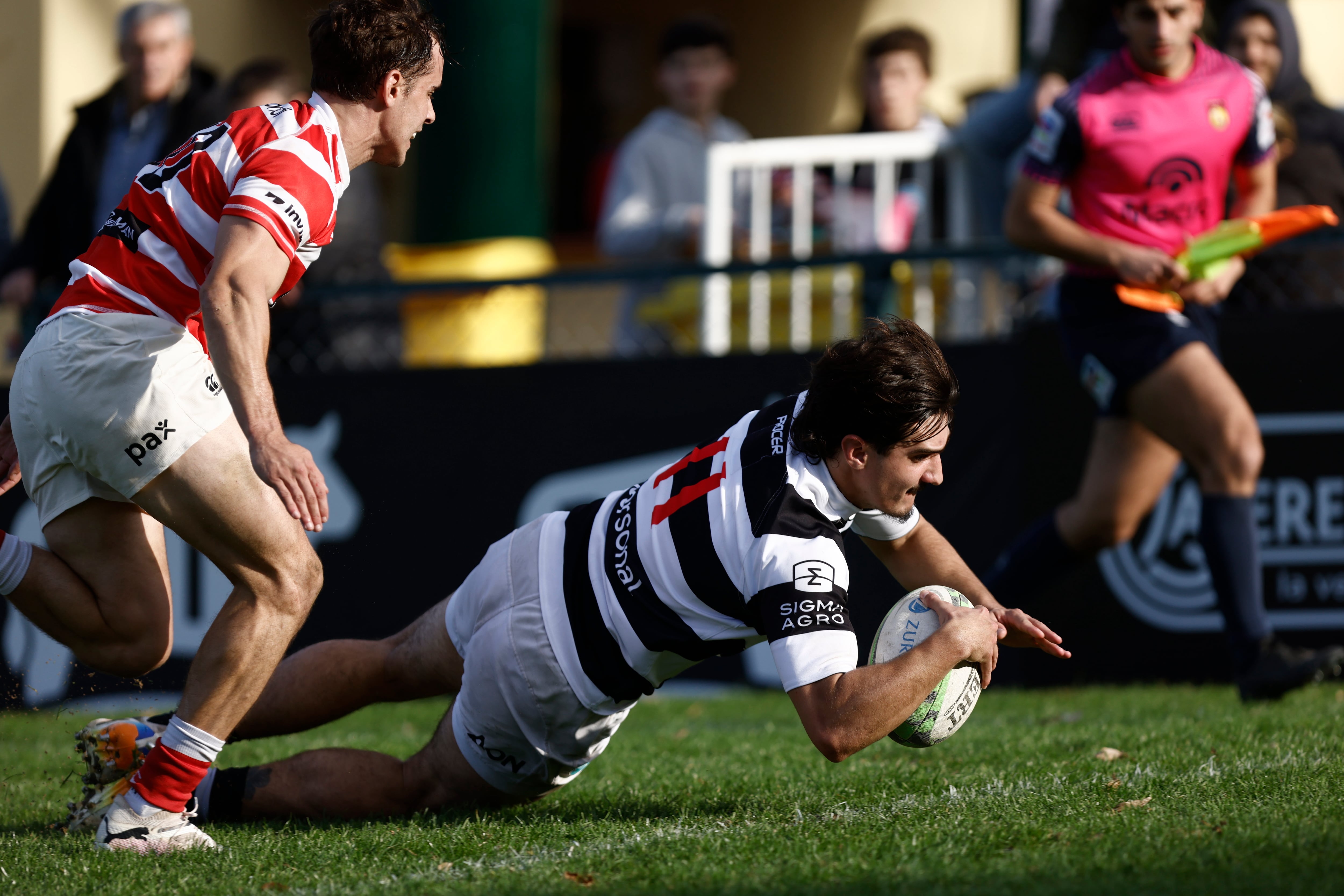 Tomás Phelan anota el primer try de CASI; no llega a evitarlo Bautista Canzani, apertura y capitán de Alumni.