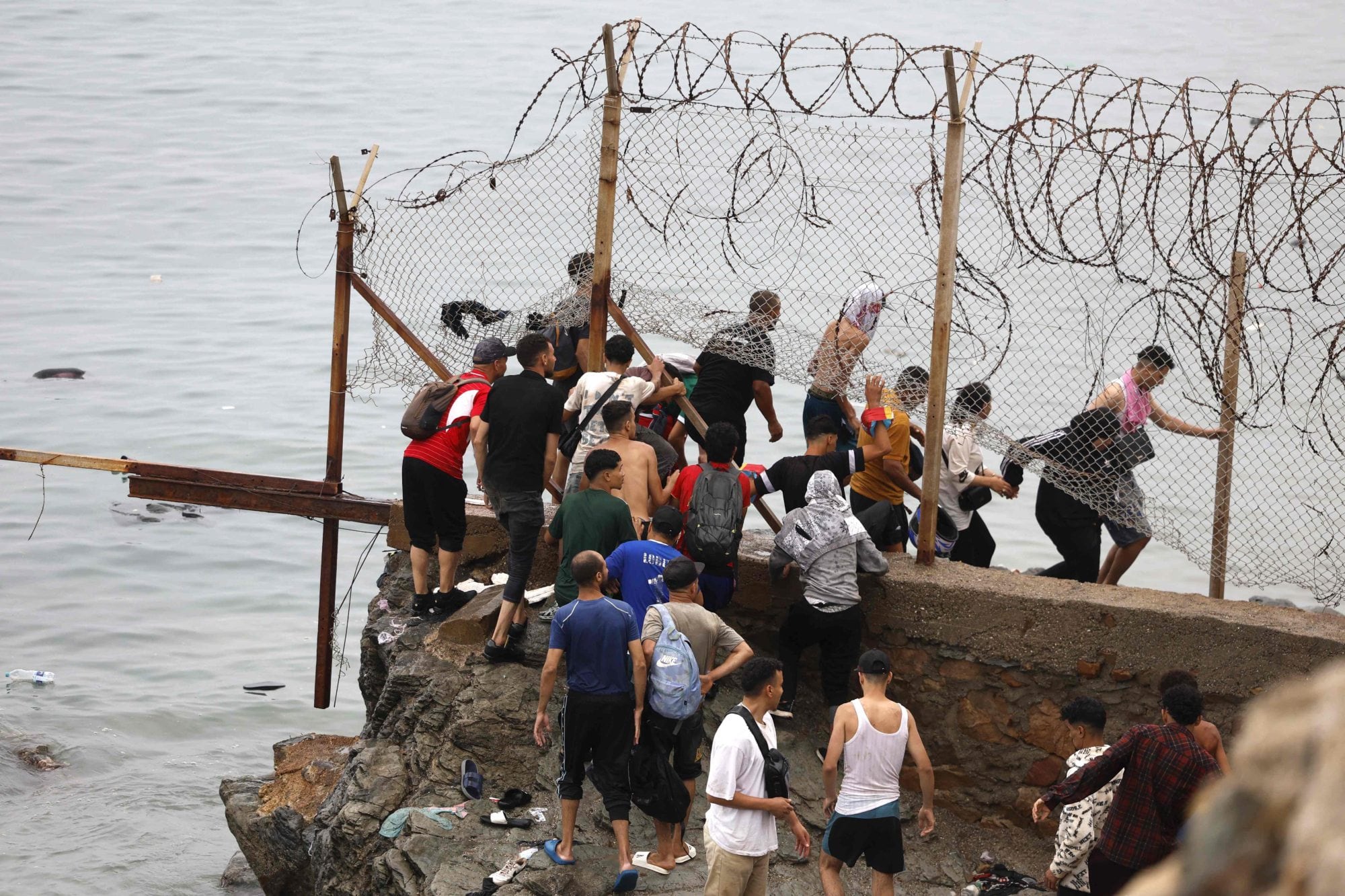 Personas se reúnen junto a la valla, cerca del lugar de los enfrentamientos, próximo a Fnideq (Castillejos), en la frontera entre Marruecos y España