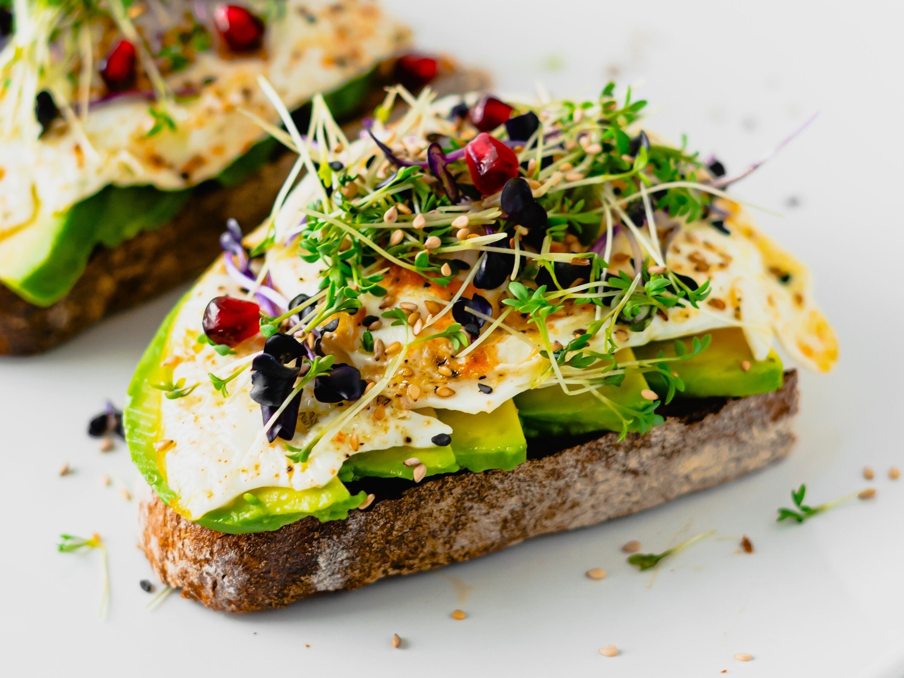 Tostadas con palta, láminas de queso y brotes