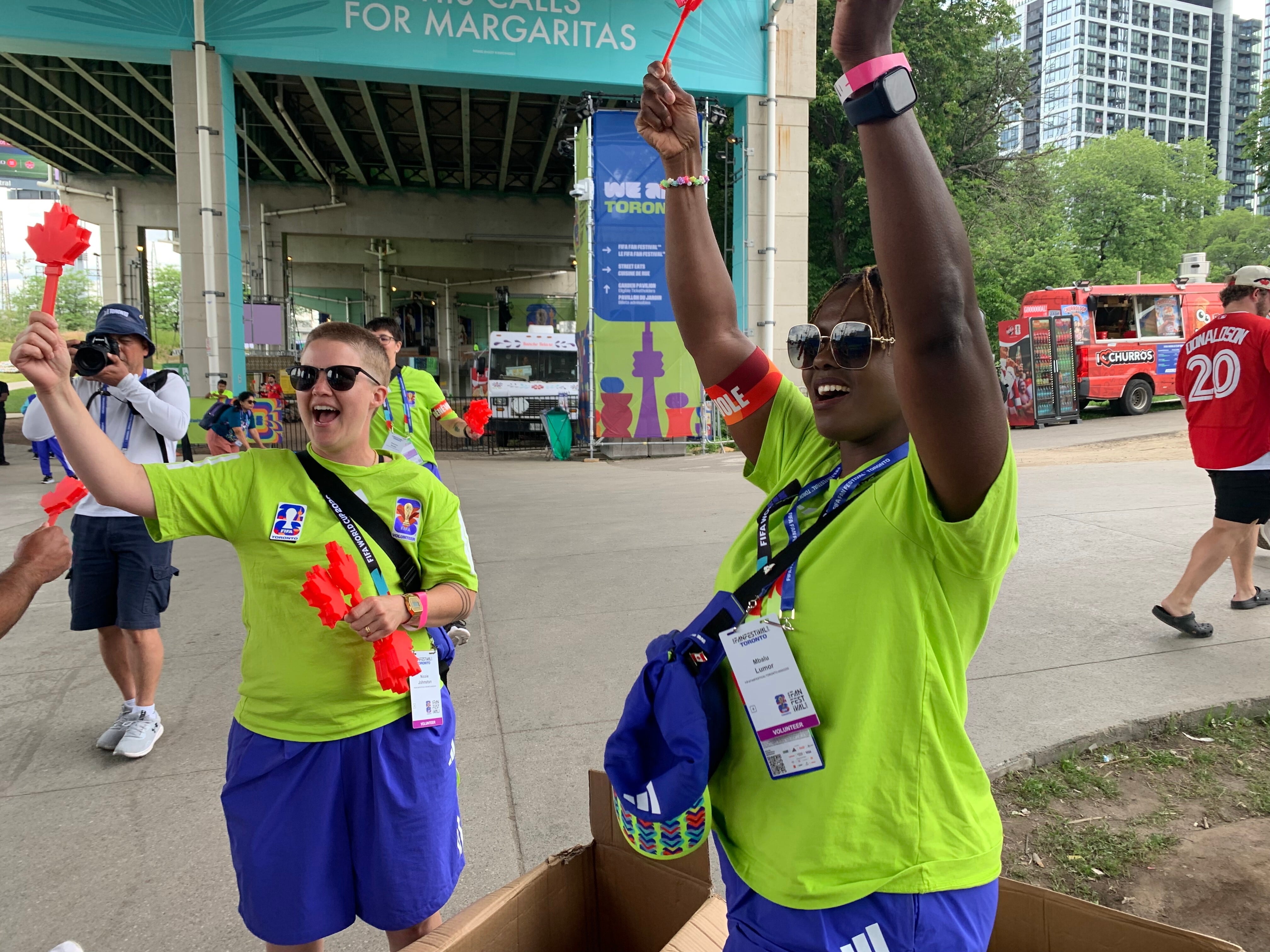 Las voluntarias Nicole Johnston (izquierda) y Mbalu Lumor (derecha) agitan aplaudidores canadienses (