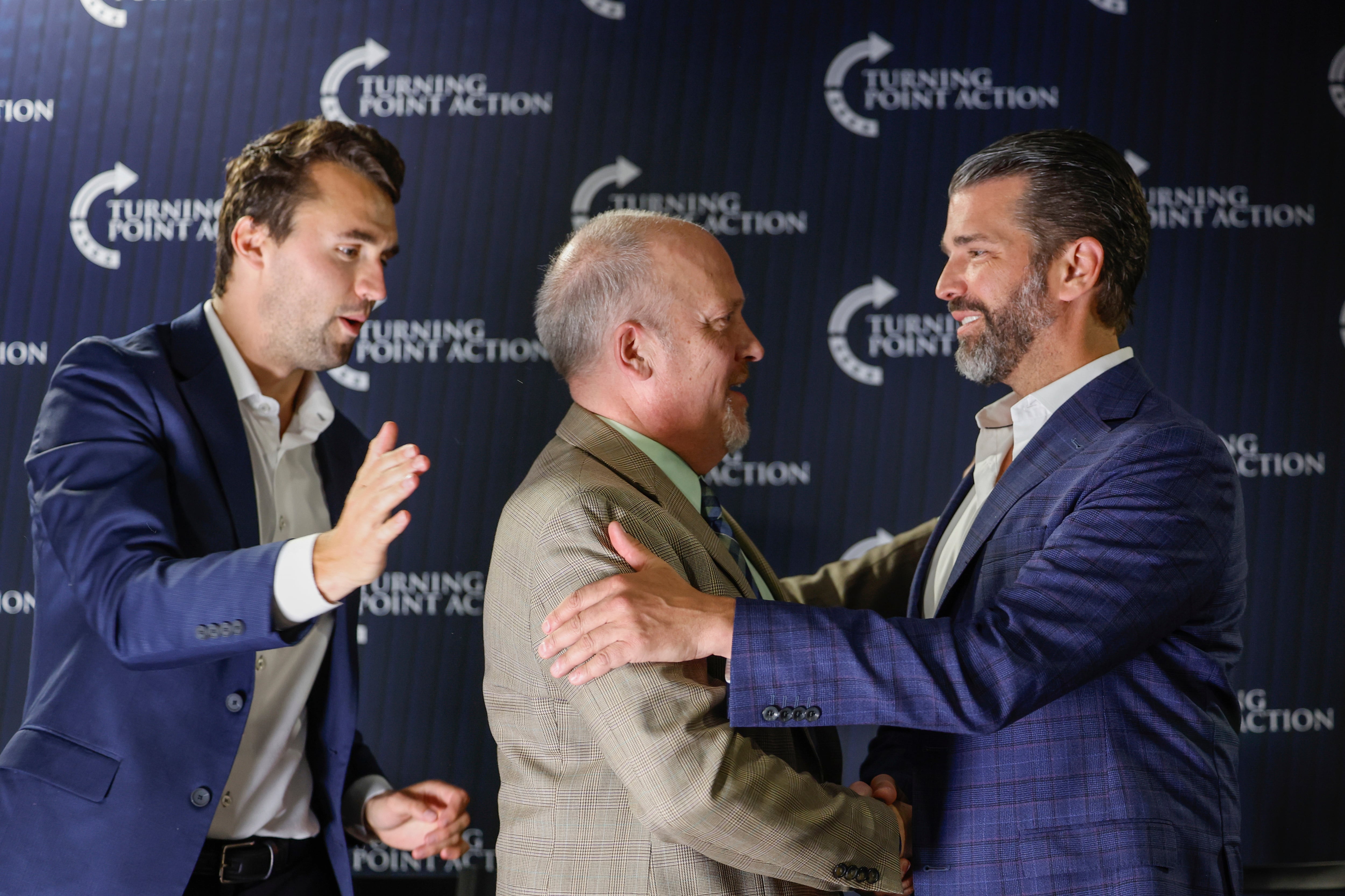 El exfiscal general de Wisconsin y candidato a la Corte Suprema del estado Brad Schimel, en el centro, saluda a Donald Trump Jr, mientras Charlie Kirk mira durante un encuentro público el lunes 17 de marzo de 2025, en Oconomowoc, Wisconsin. (AP foto/Jeffrey Phelps)