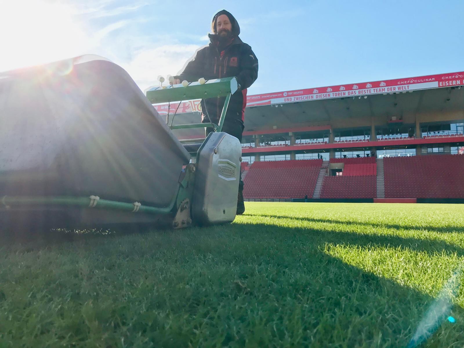 Máquina en mano, Alejandro recorta el césped del estadio de Union Berlin