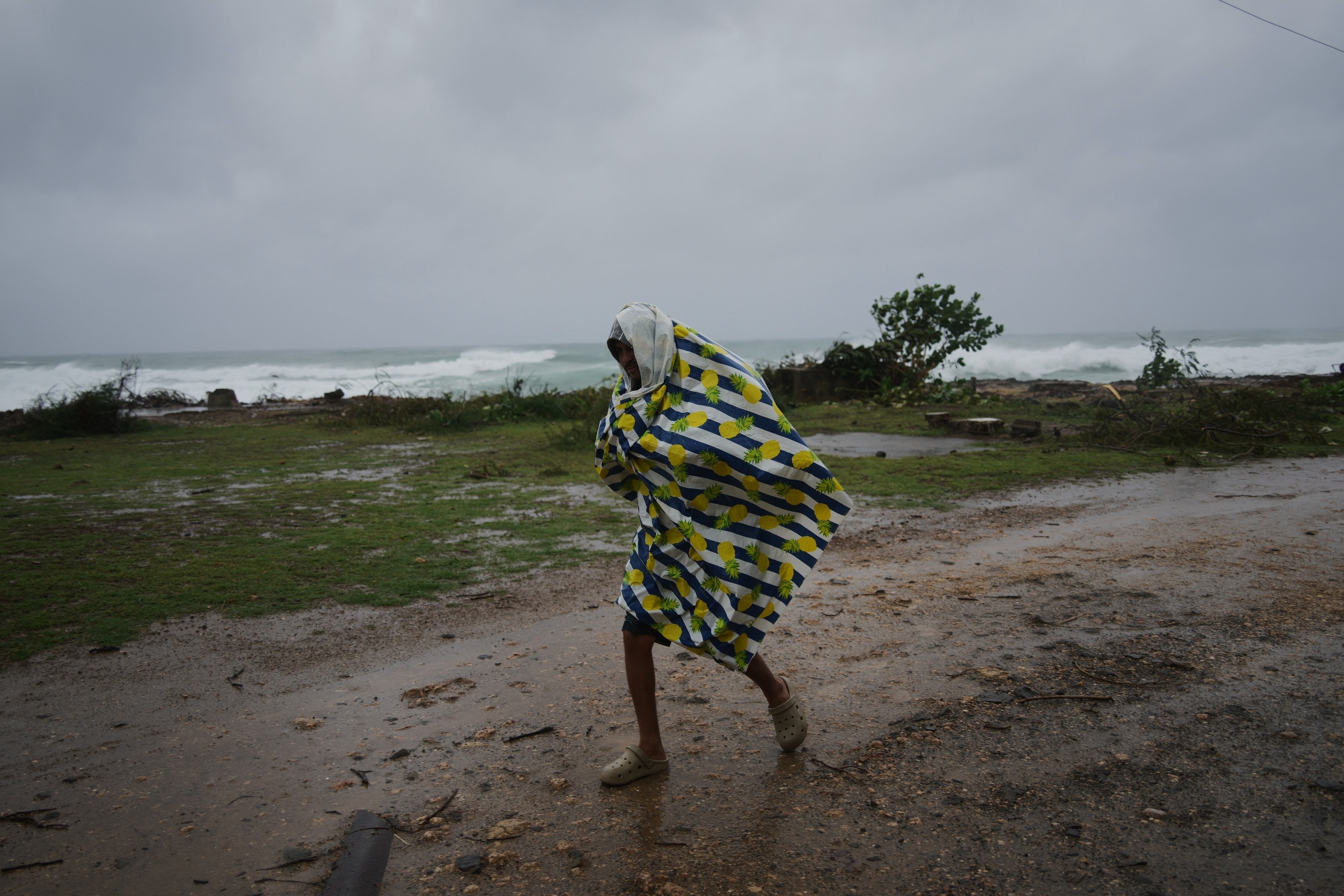 Un hombre camina bajo la lluvia antes de la llegada del huracán Melissa, en Canizo, una localidad en Santiago de Cuba