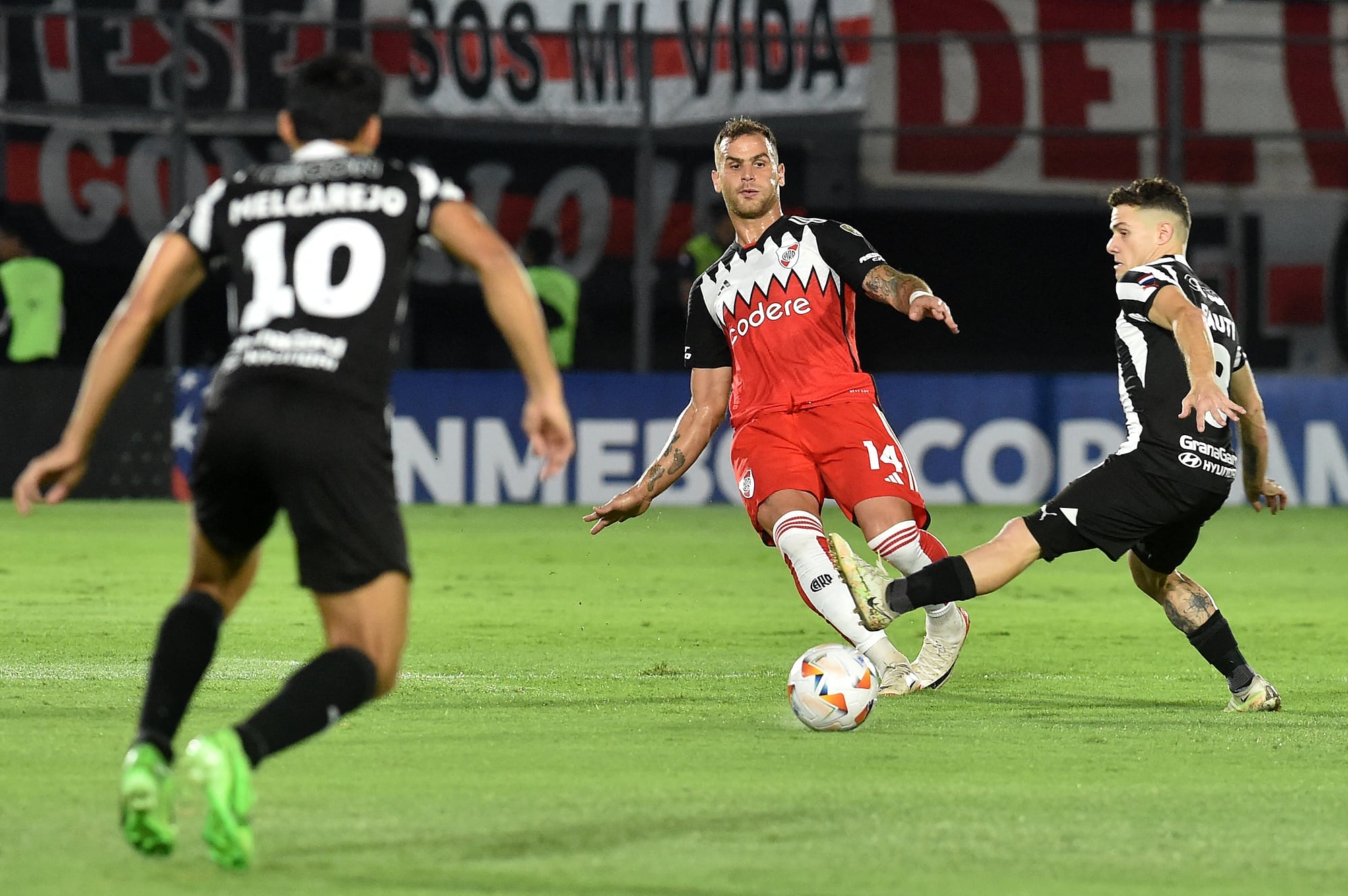 González Pirez da un pase entre dos jugadores de Libertad