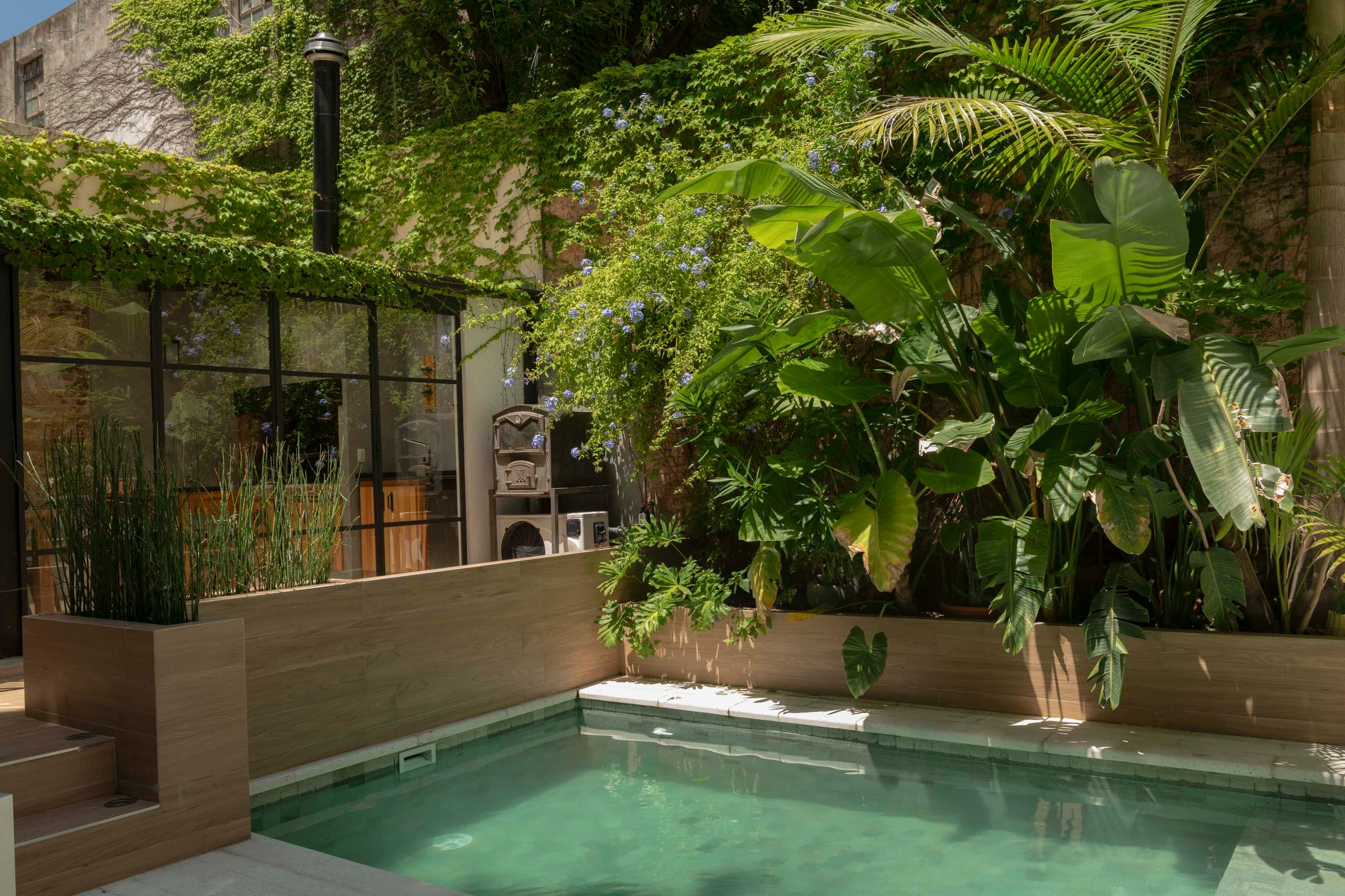 En el espacio entre la pileta y el quincho, un horno de pan disimula el equipo exterior del AC.