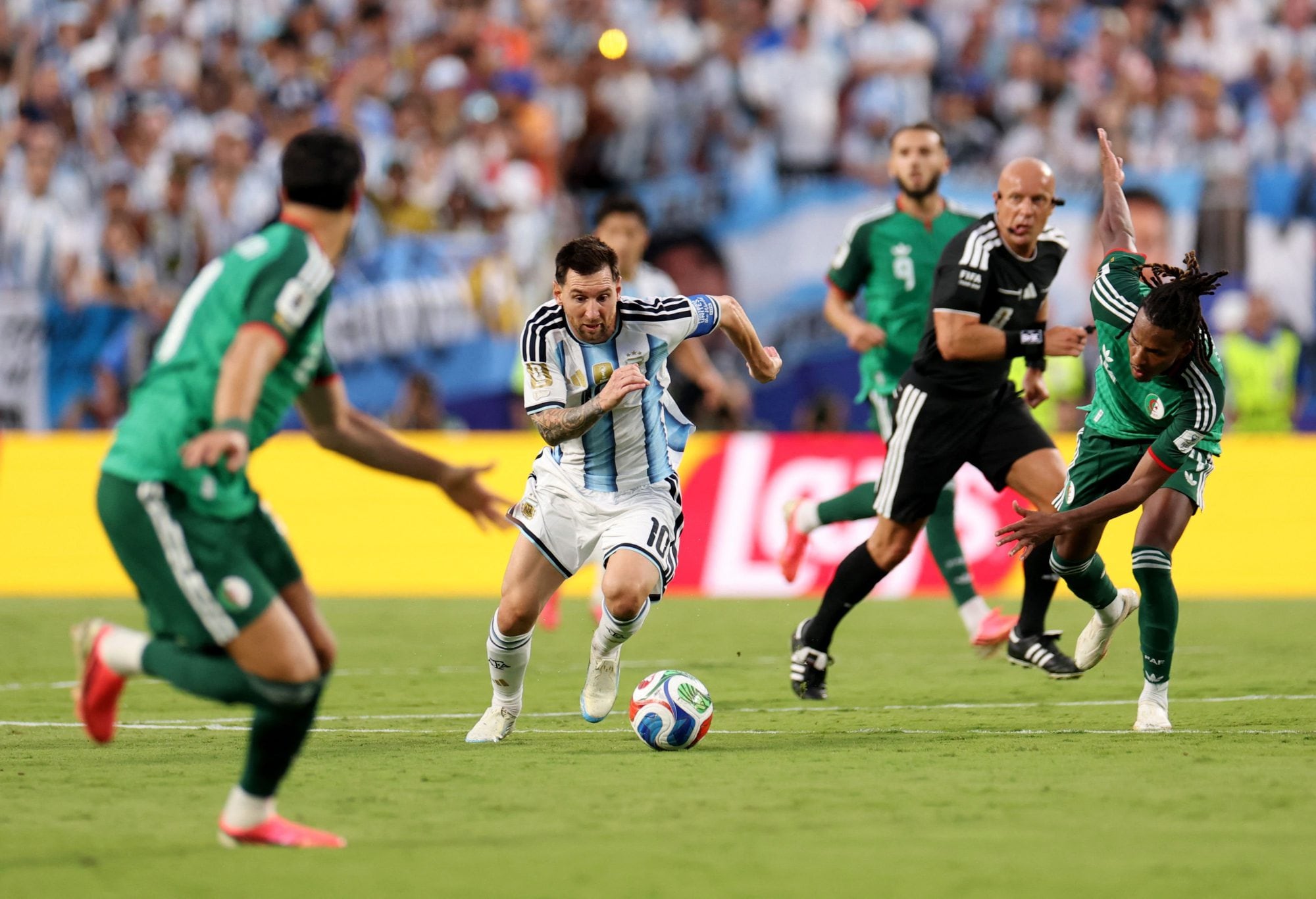 Lionel Messi encara con la pelota ante la marca de los jugadores de Argelia