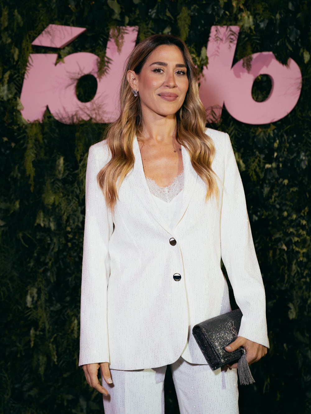 Jimena Barón, con una traje off white con botones negros, sobre top lencero a tono, que acompañó con clutch en negro con detalles plateados