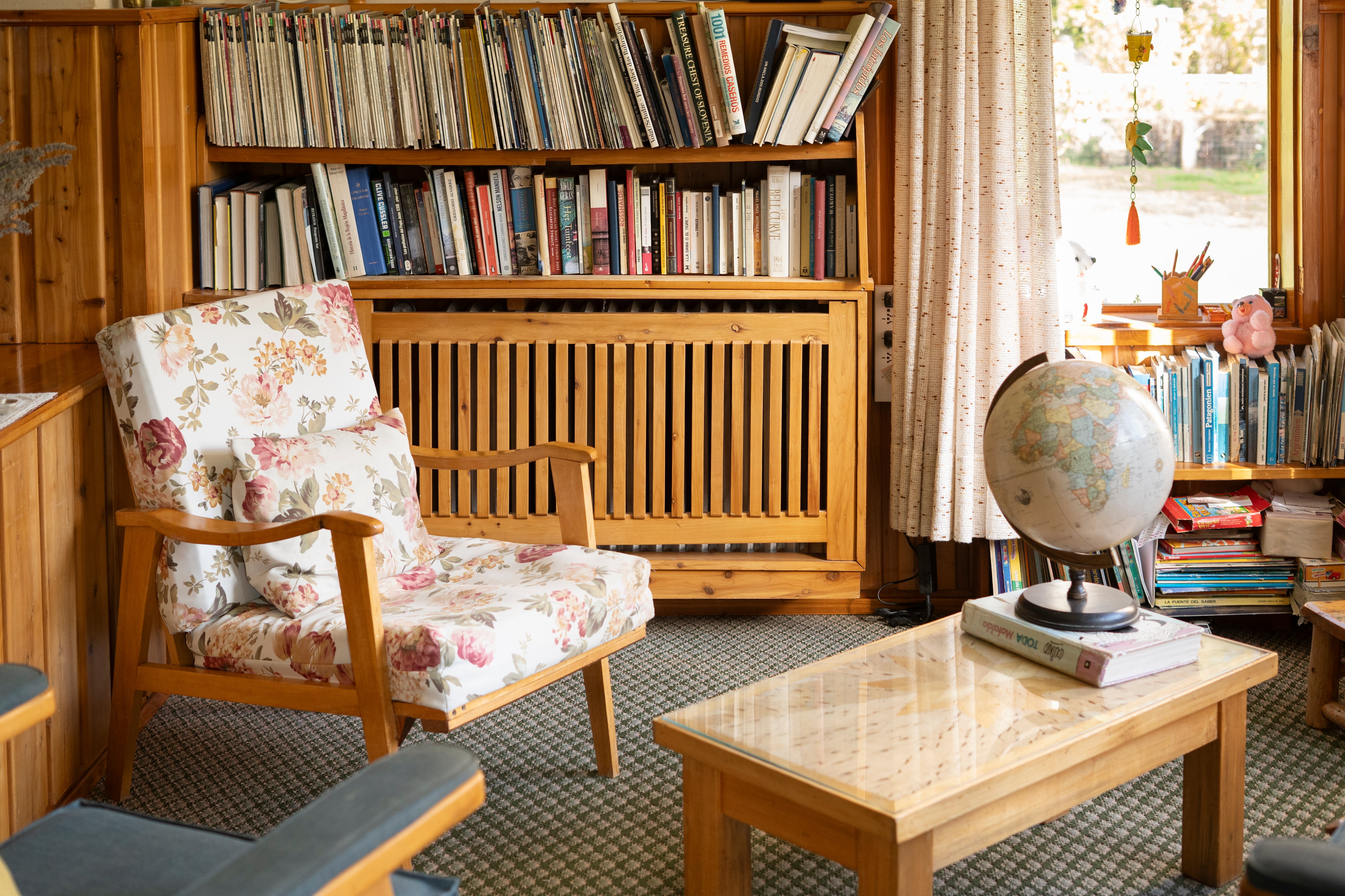 Un rincón de la hostería, con biblioteca y sillones tapizados con flores
