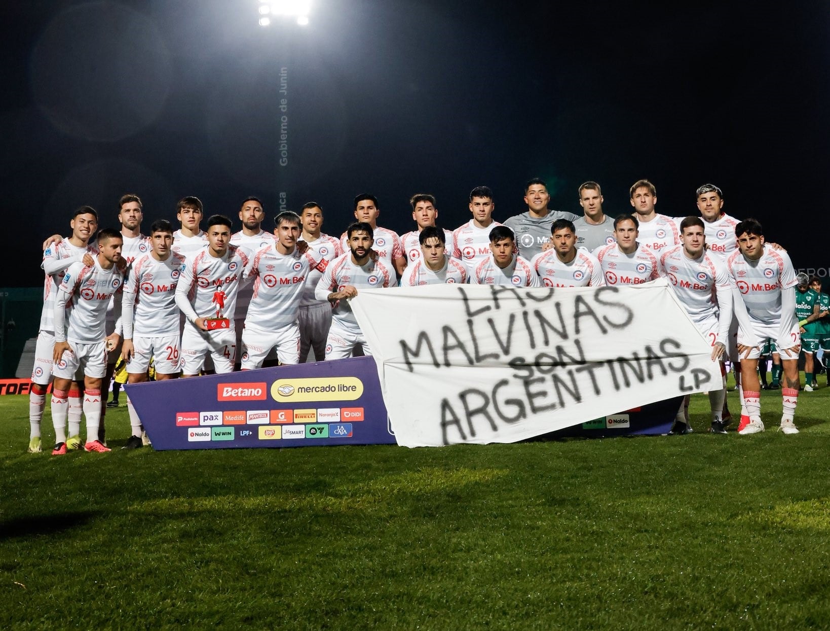 El plantel de Argentinos Juniors antes de jugar con Sarmiento, con la bandera y la leyenda: