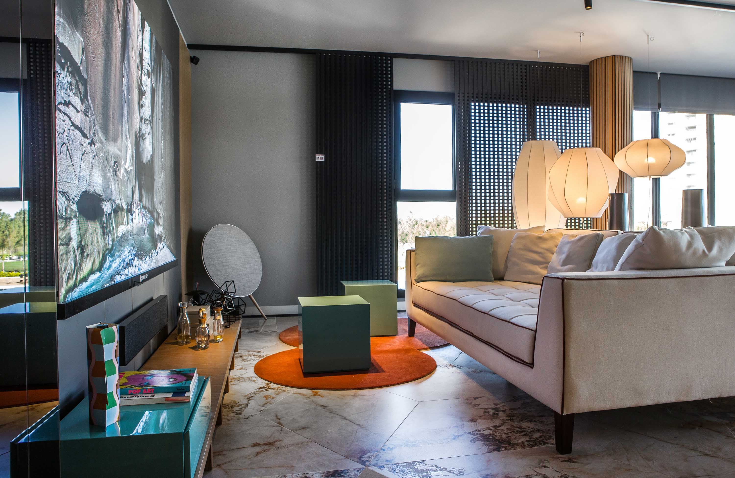 Piso de porcelanatos 'Sur Beige' de gran formato y 'Mirror Glow' (San Lorenzo Design). Sofá Lucía (Poltron Design) con géneros de Zanav. Para moderar la luz cerca de la pantalla, parasol corredizo 'Mutsharabi', un lanzamiento 2026 de Shawer.