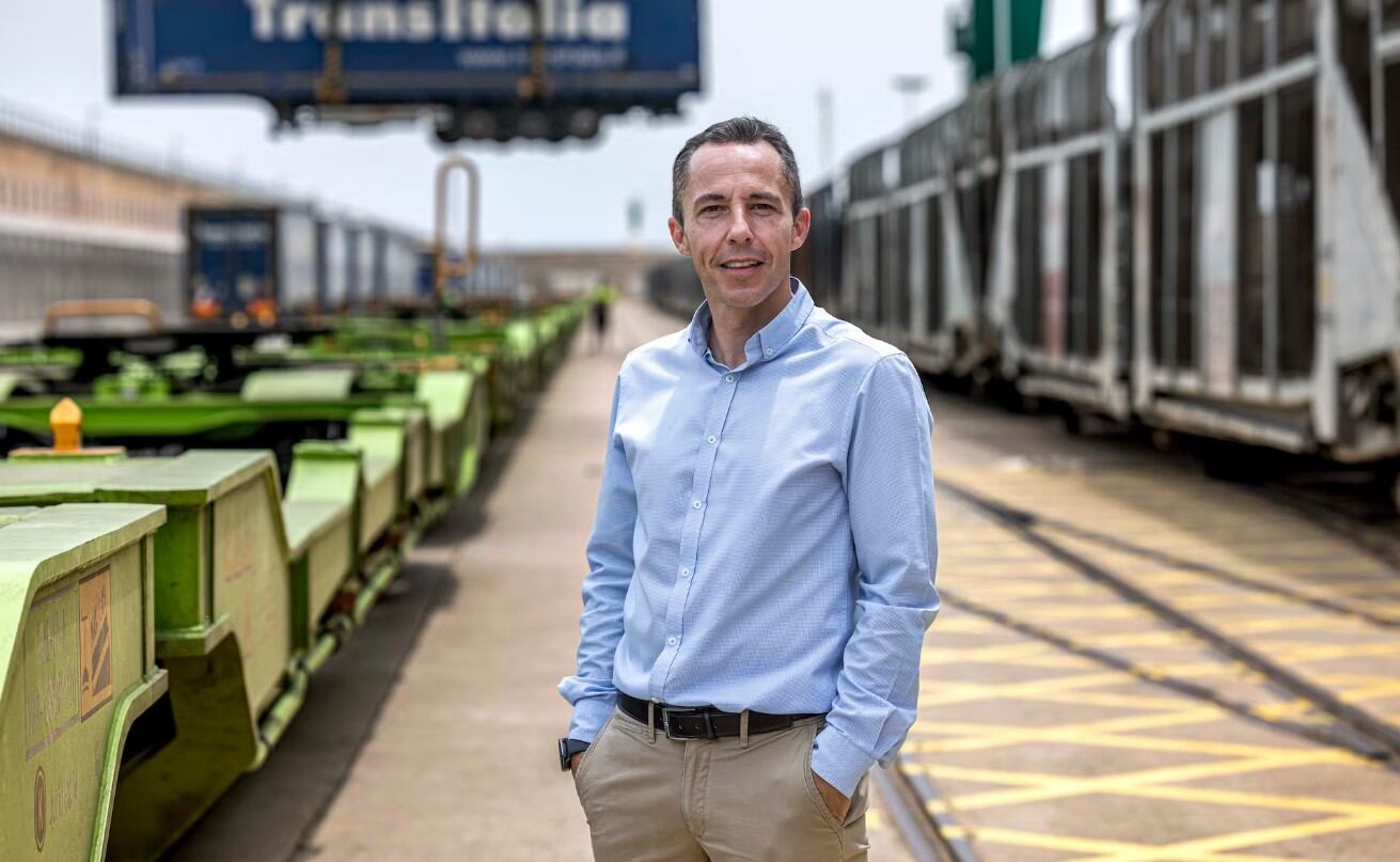 Carlos Pereda, subdirector de Tramesa, en el Puerto de Valencia junto al tren que traslada los camiones desde Valencia a Madrid