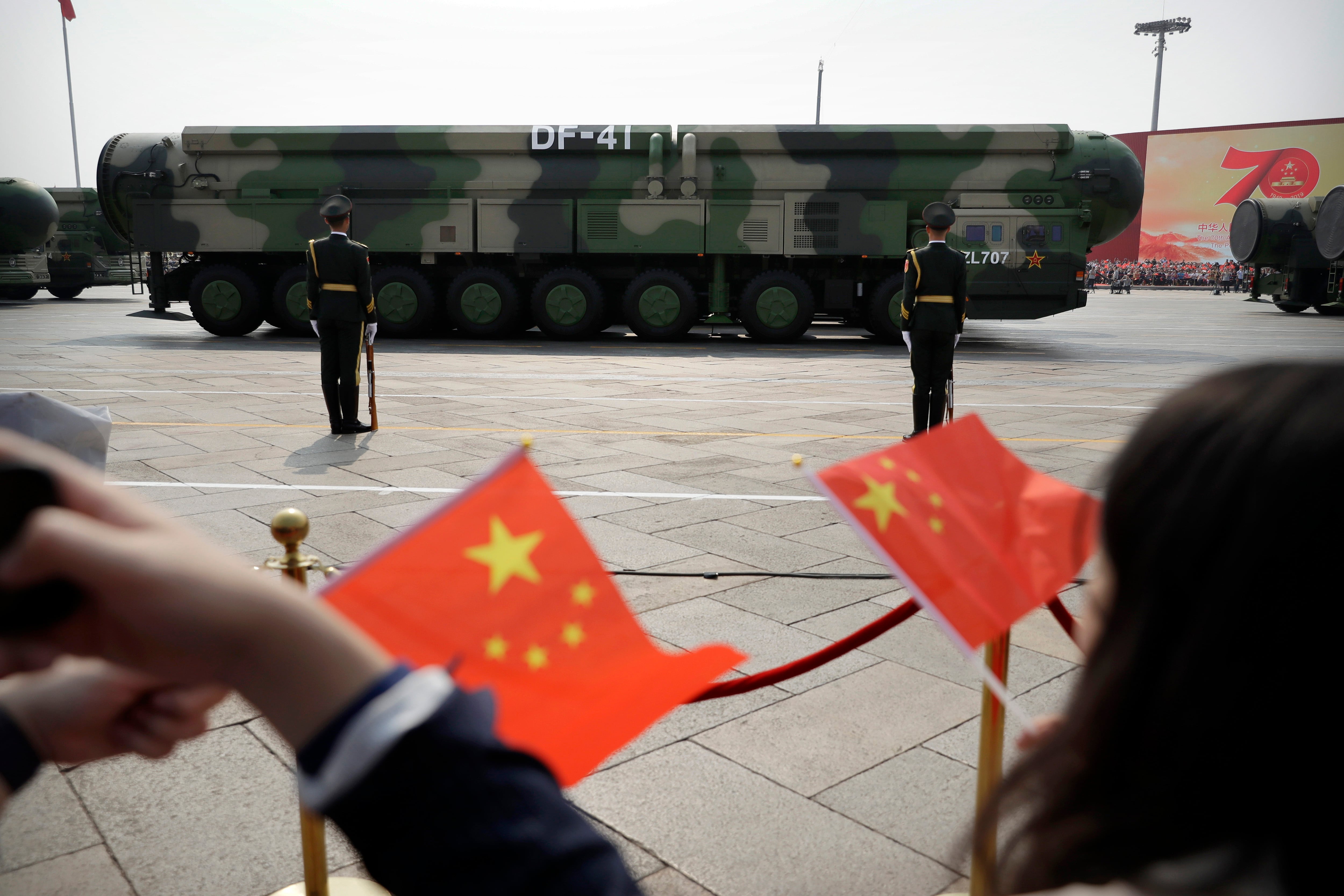 ARCHIVO. Espectadores ondean banderas chinas mientras vehículos militares con misiles balísticos (AP Foto/Mark Schiefelbein, Archivo)