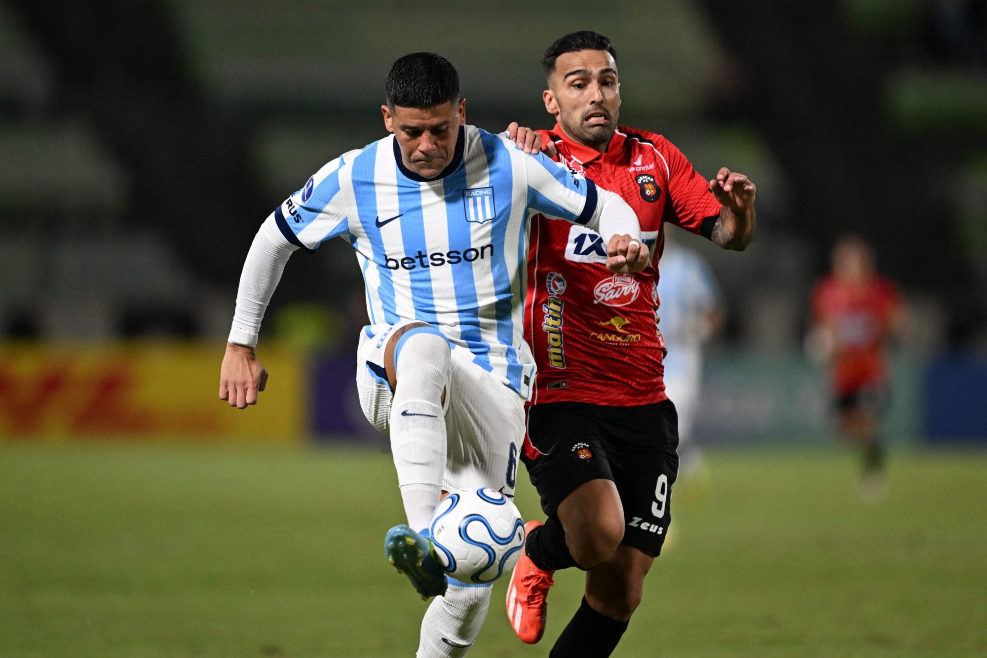 Marcos Rojo se lleva la pelota ante la presión de Adrián Fernández, de Caracas; Racing igualó en Venezuela por la Copa Sudamericana
