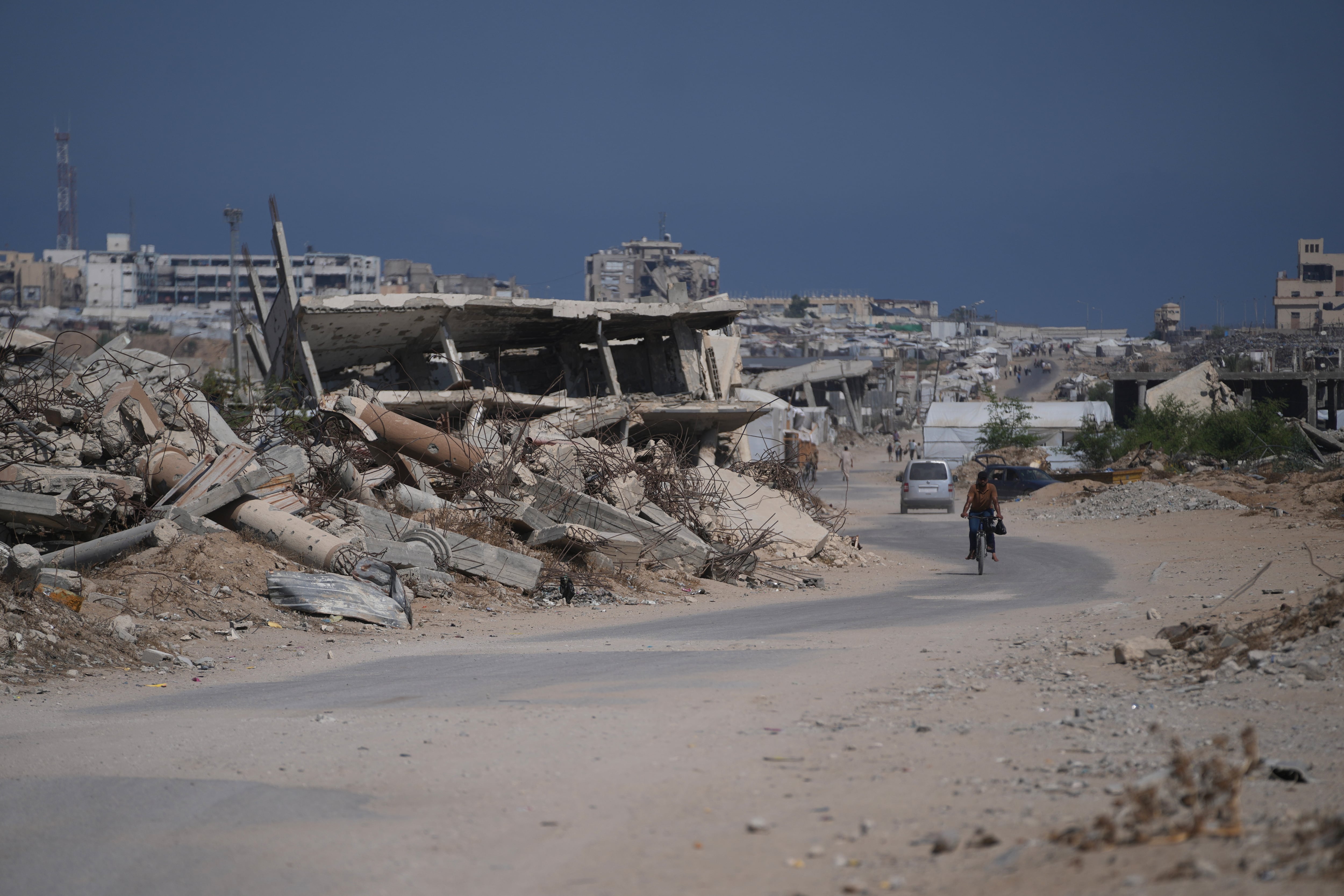Un palestino pasa en bicicleta junto a escombros de edificios destruidos durante la guerra entre Israel y Hamás, en Jan Yunis, en el sur de Gaza