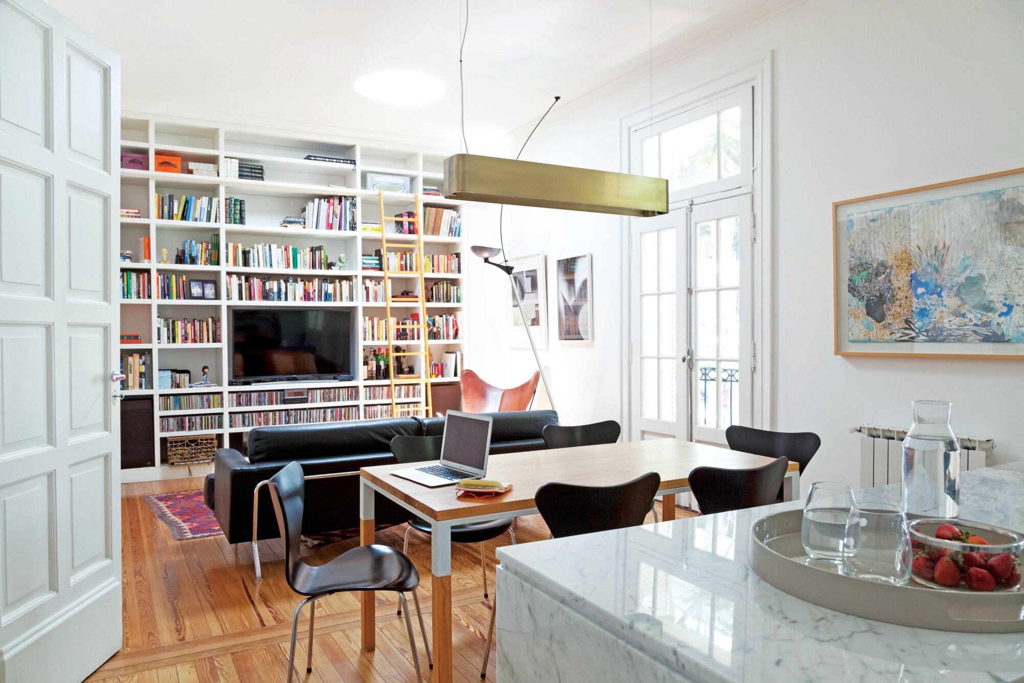 Detrás de la silla BKF, un regalo para la arquitecta: obras de Platz (Galería Praxis). La biblioteca con escalera (Estudio Trama) abarca la totalidad de la pared lateral.