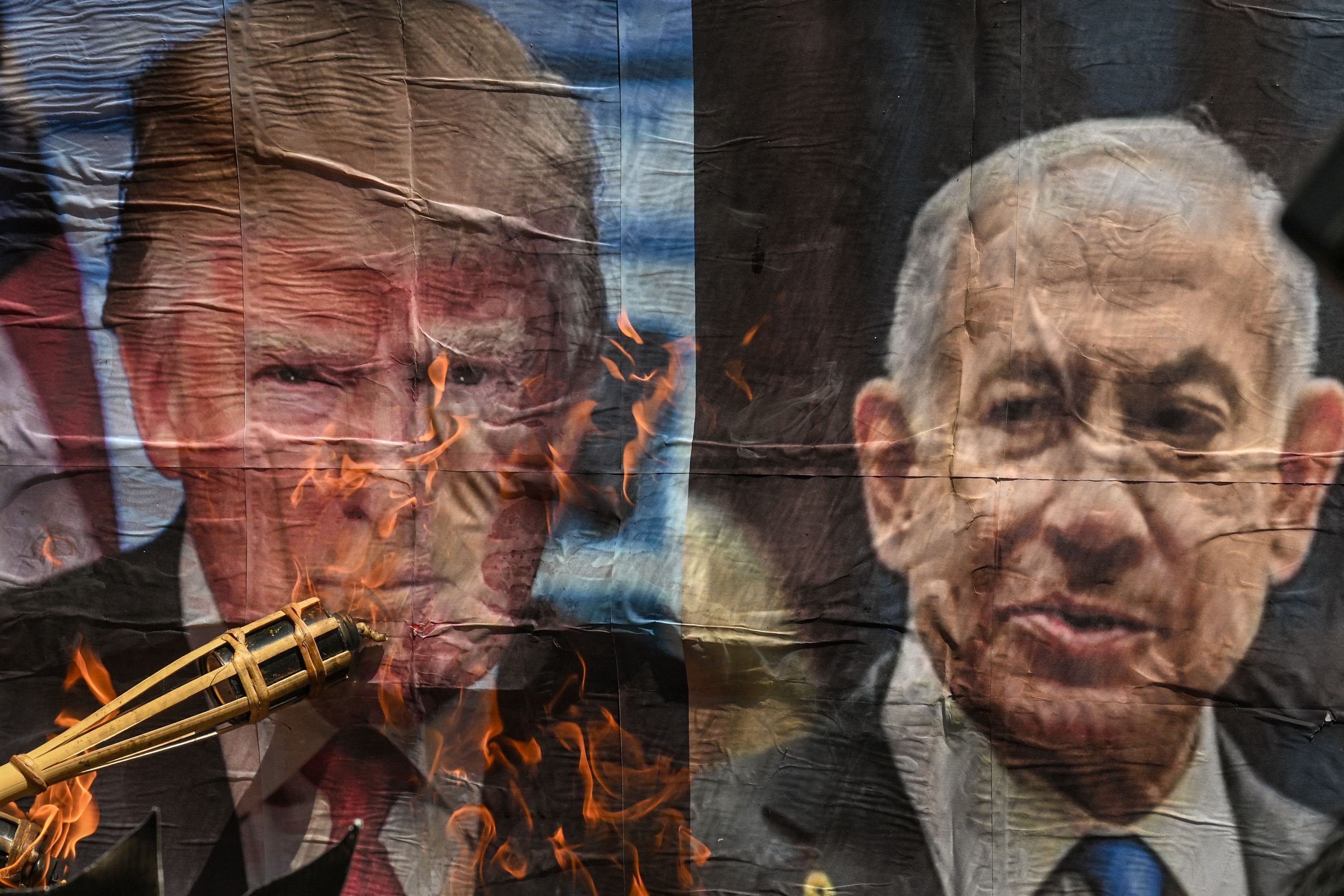 Un hombre quema una fotografía del presidente estadounidense Donald Trump y del primer ministro israelí Benjamin Netanyahu