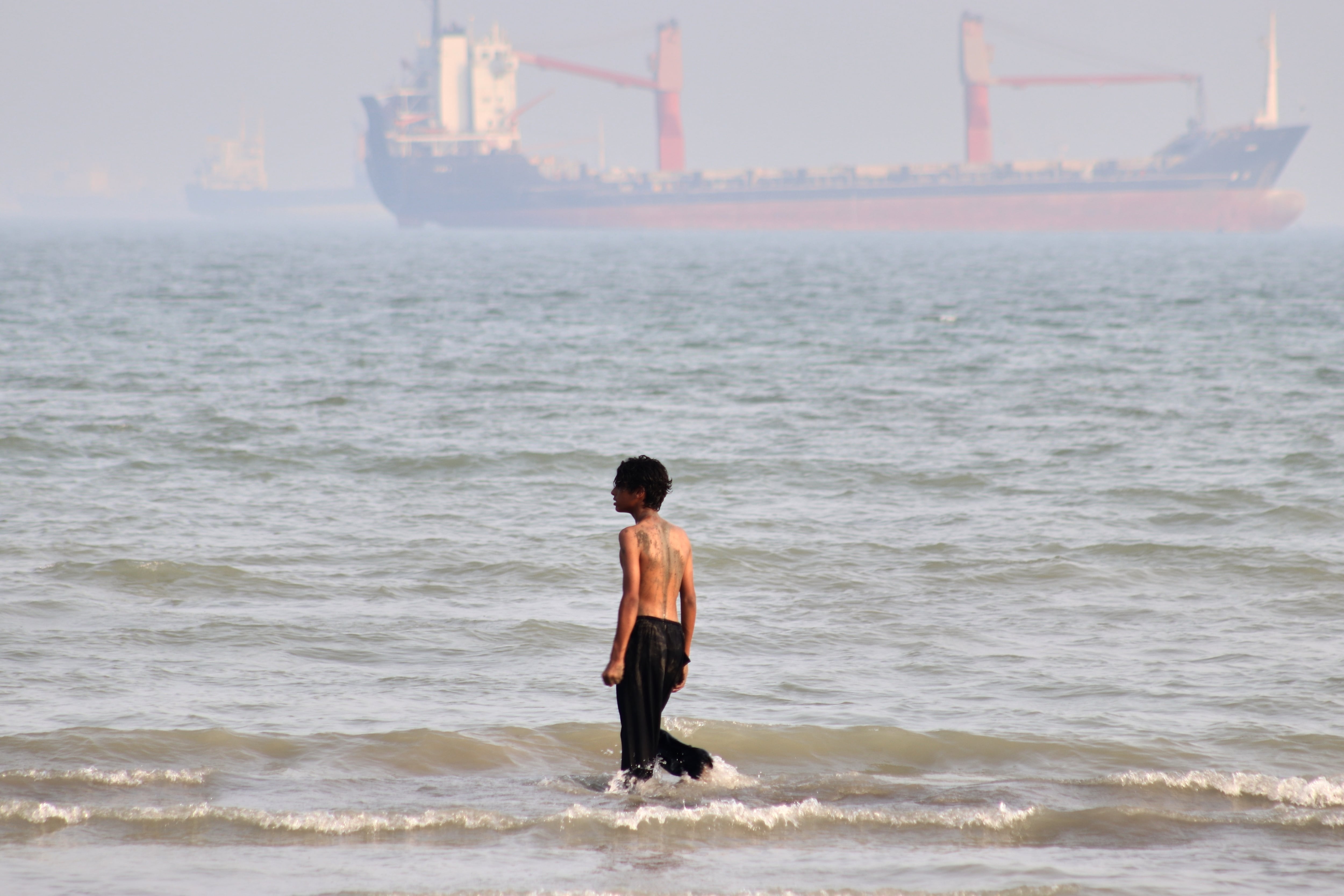 Un niño camina por la orilla mientras buques comerciales están fondeados en el estrecho de Ormuz, ante la costa de Bandar Abbas, Irán, el 31 de agosto de 2026. (Razieh Poudat/ISNA vía AP)