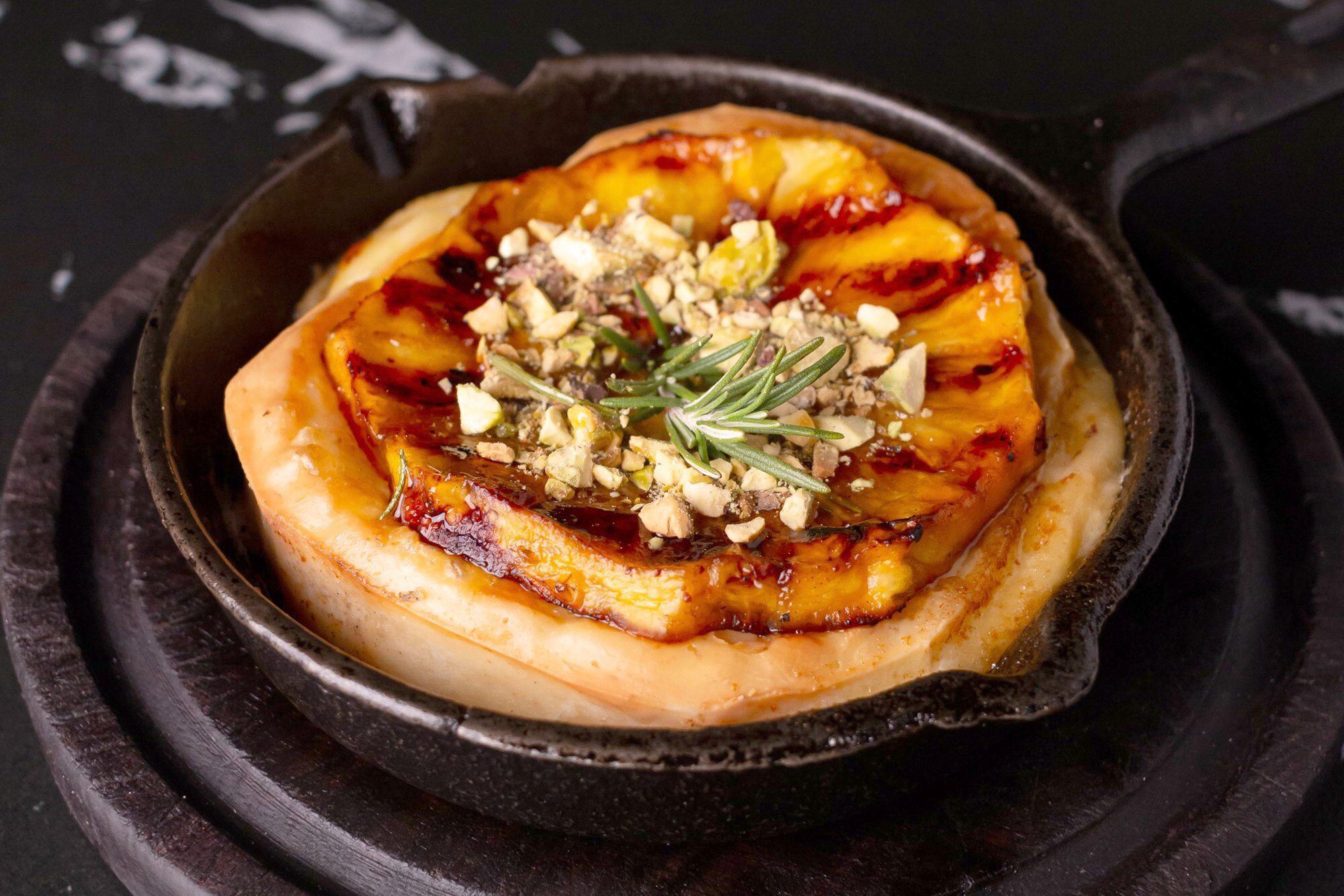 Provoleta con ananá grillado, miel y cubierta con pistachos, del restaurante Hierro