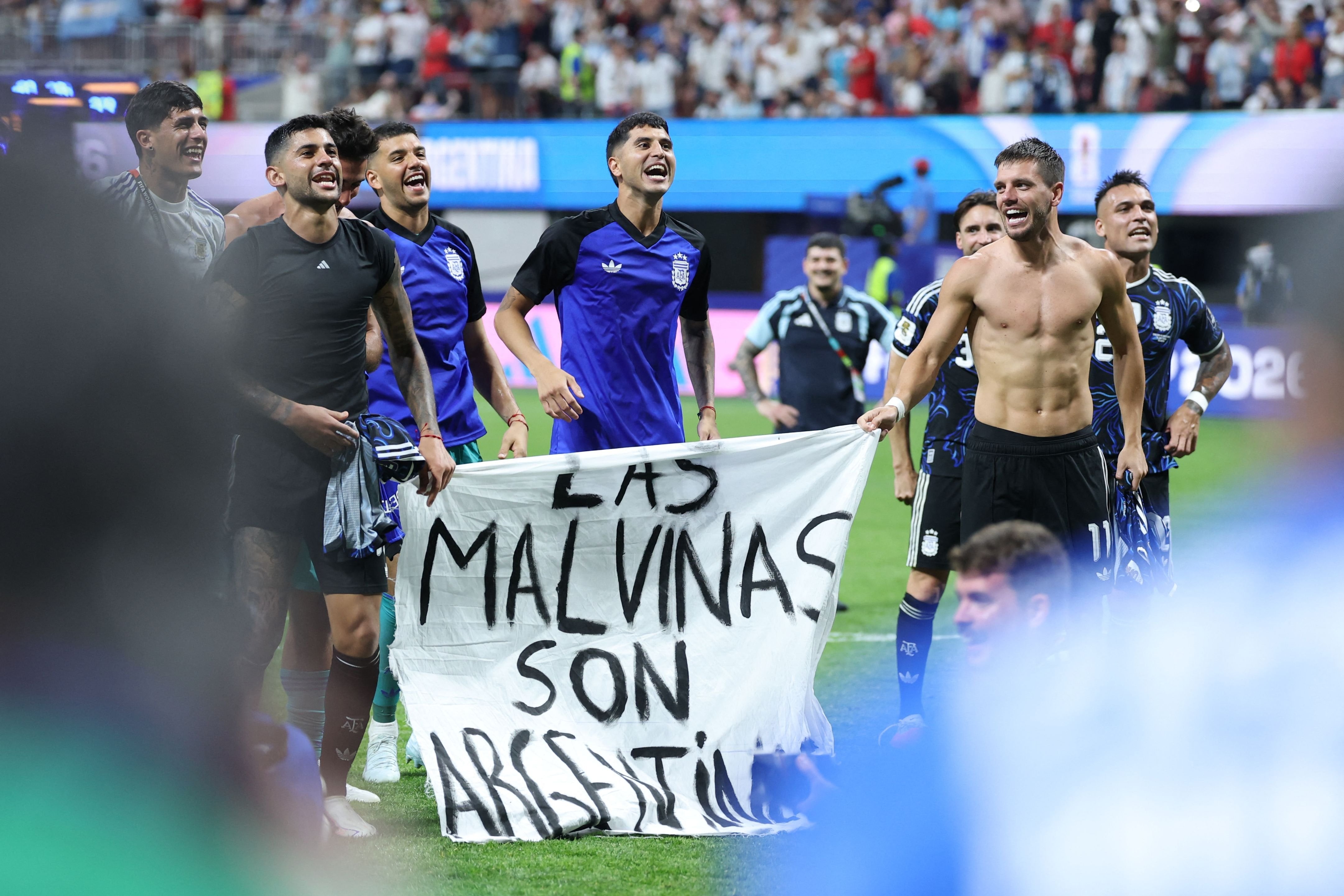 Giovani Lo Celso y Cristian Romero sostienen la bandera; la FIFA analiza posibles sanciones, que en principio serían solo económicas