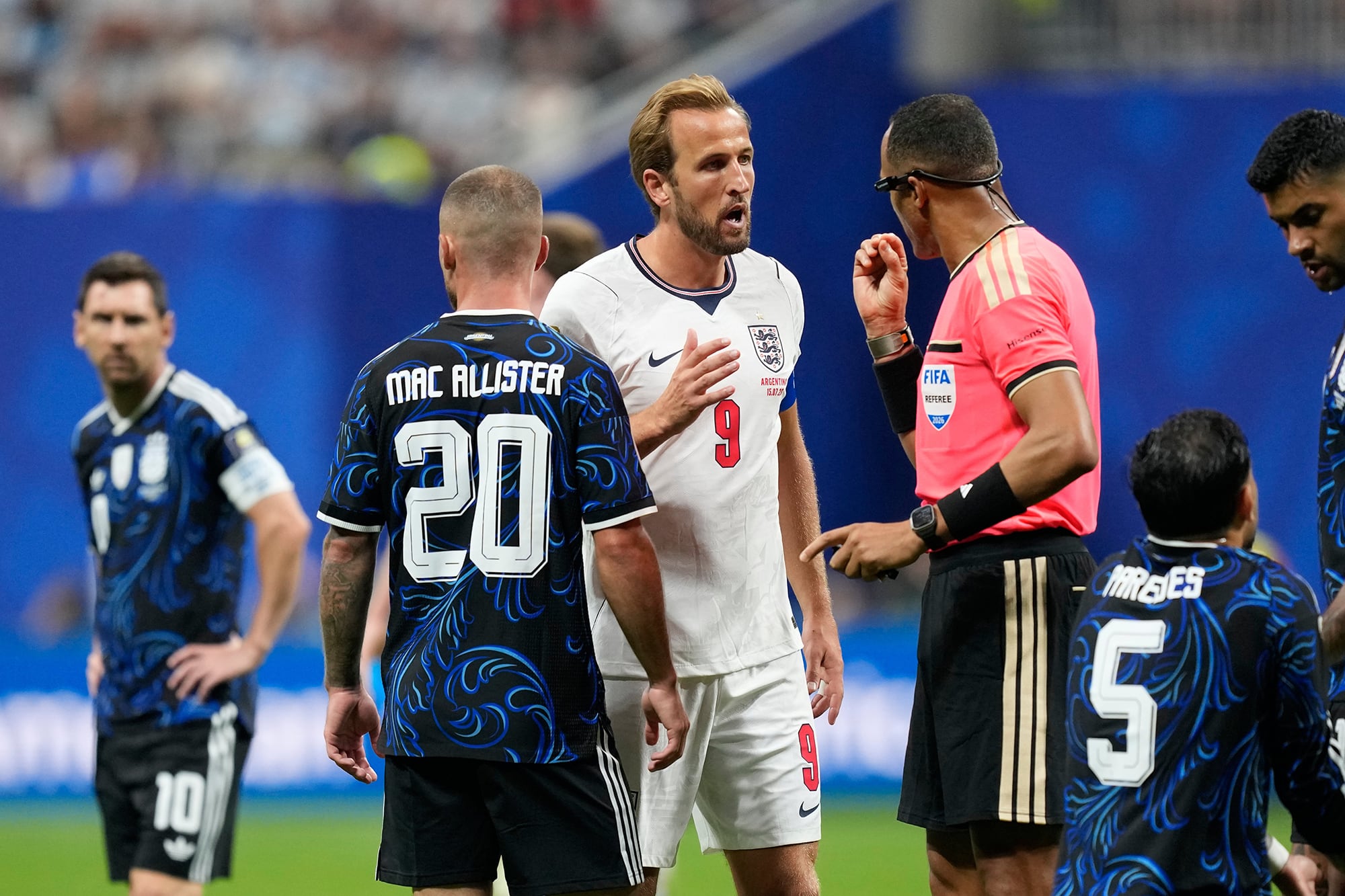 El árbitro Ismail Elfath habla con Harry Kane con Lionel Messi en el fondo y Alexis Mac Allister espaladas