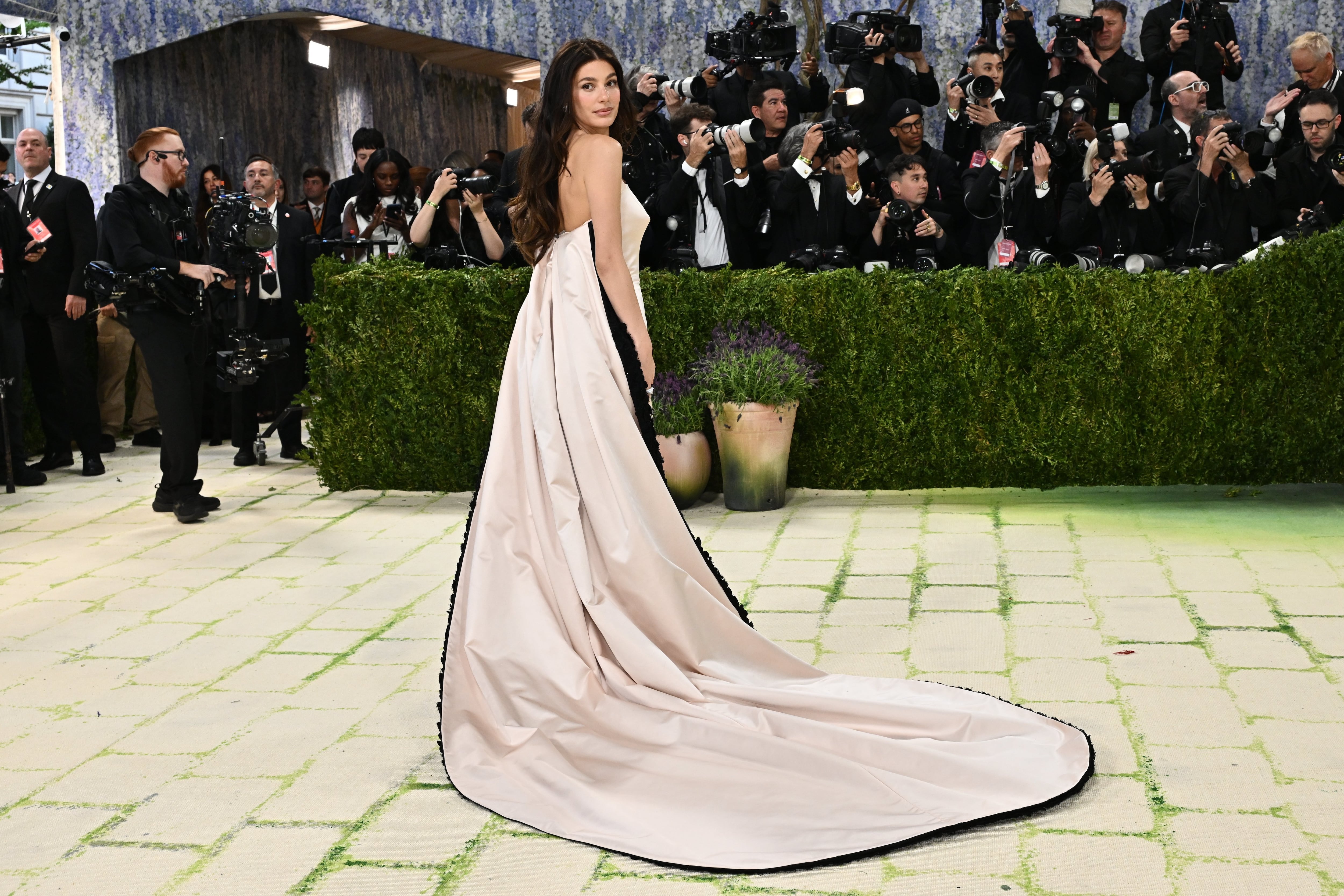 Camila Morrone combinó un clásico vestido off white de Tory Burch con una larga capa bicolor