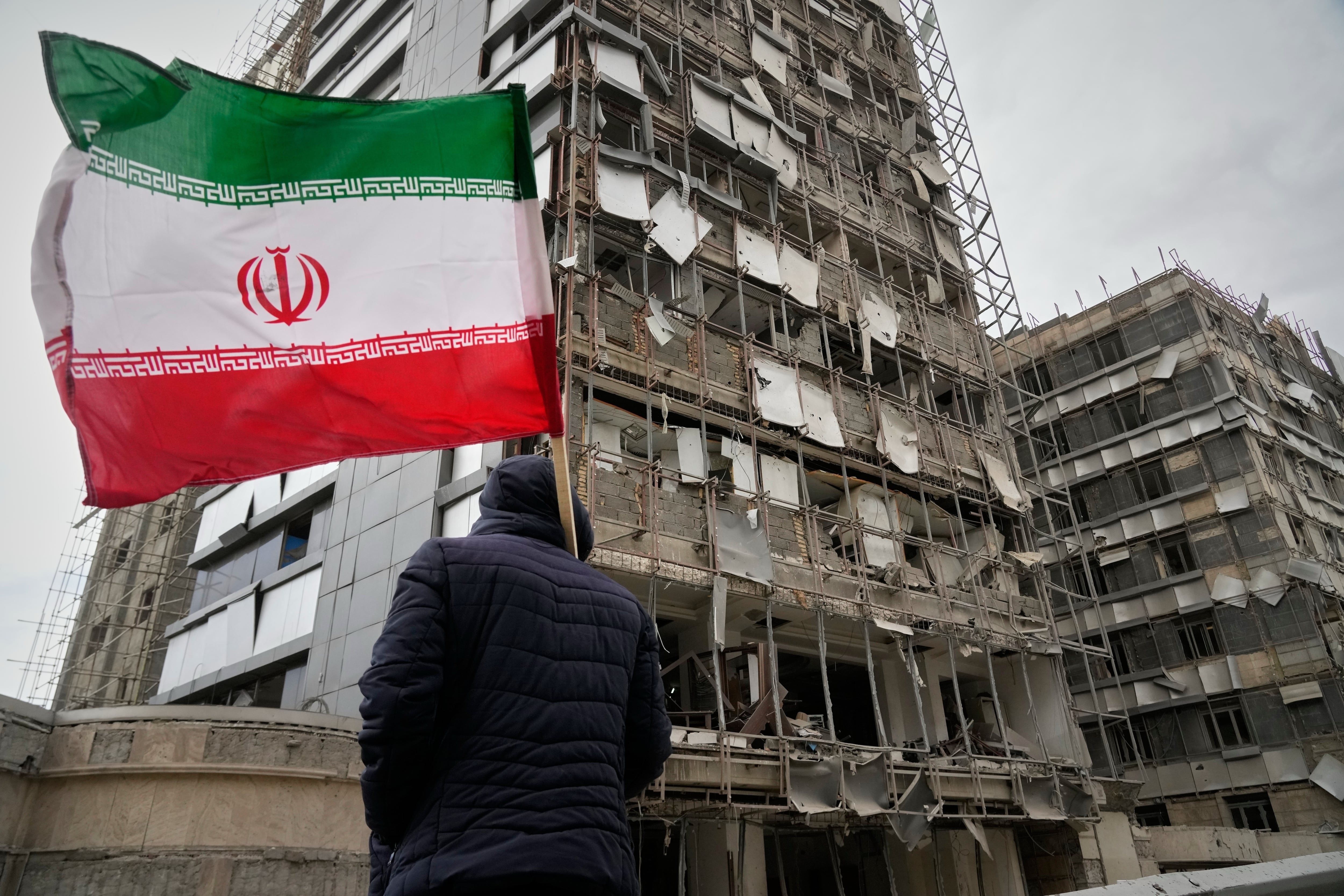 Un hombre sujeta una bandera iraní tras un ataque en Teherán, Irán