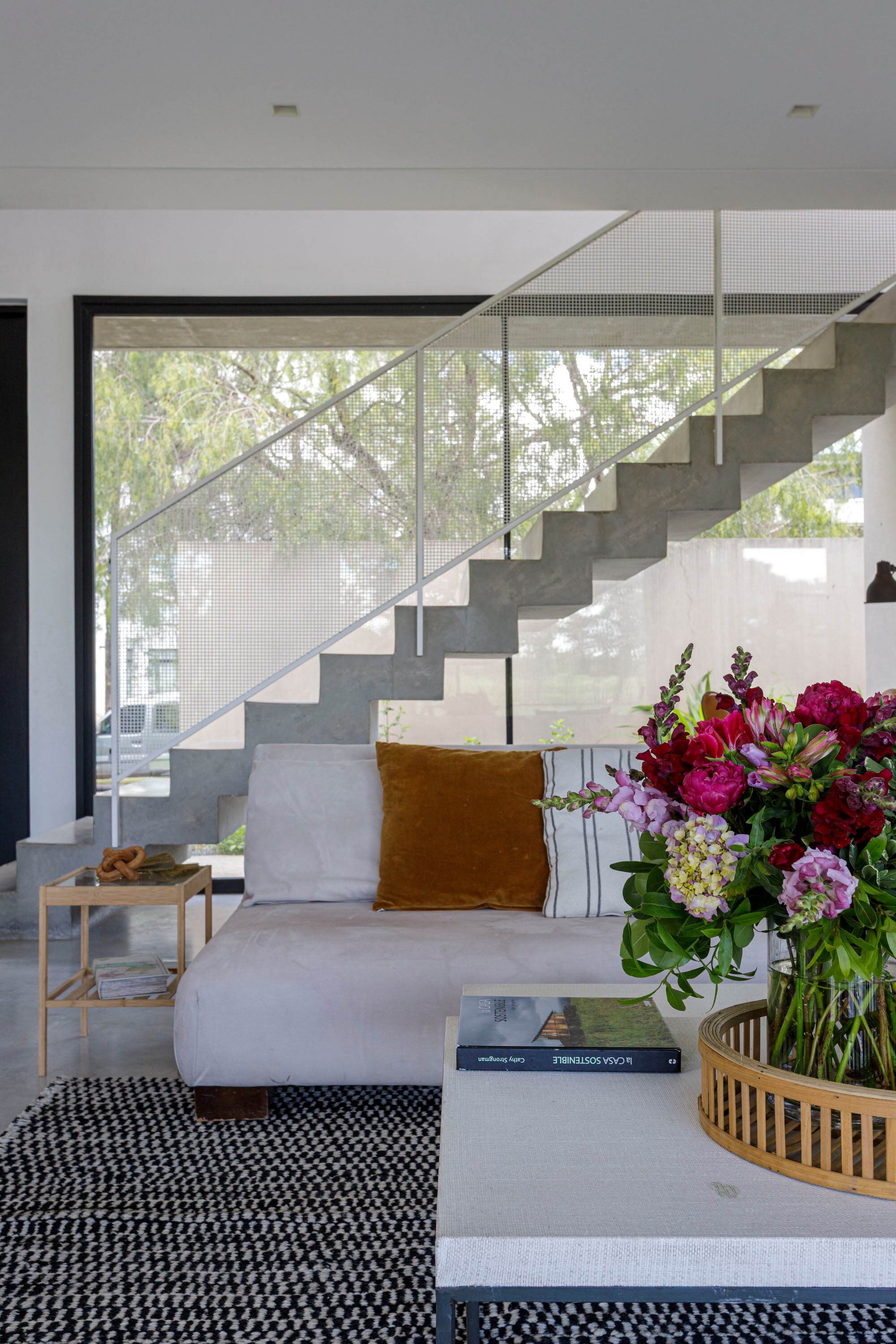 Vista hacia la calle, con la escalera de hormigón como perfil sólido y dinámico. Arreglo floral de Alejandra Raimúndez