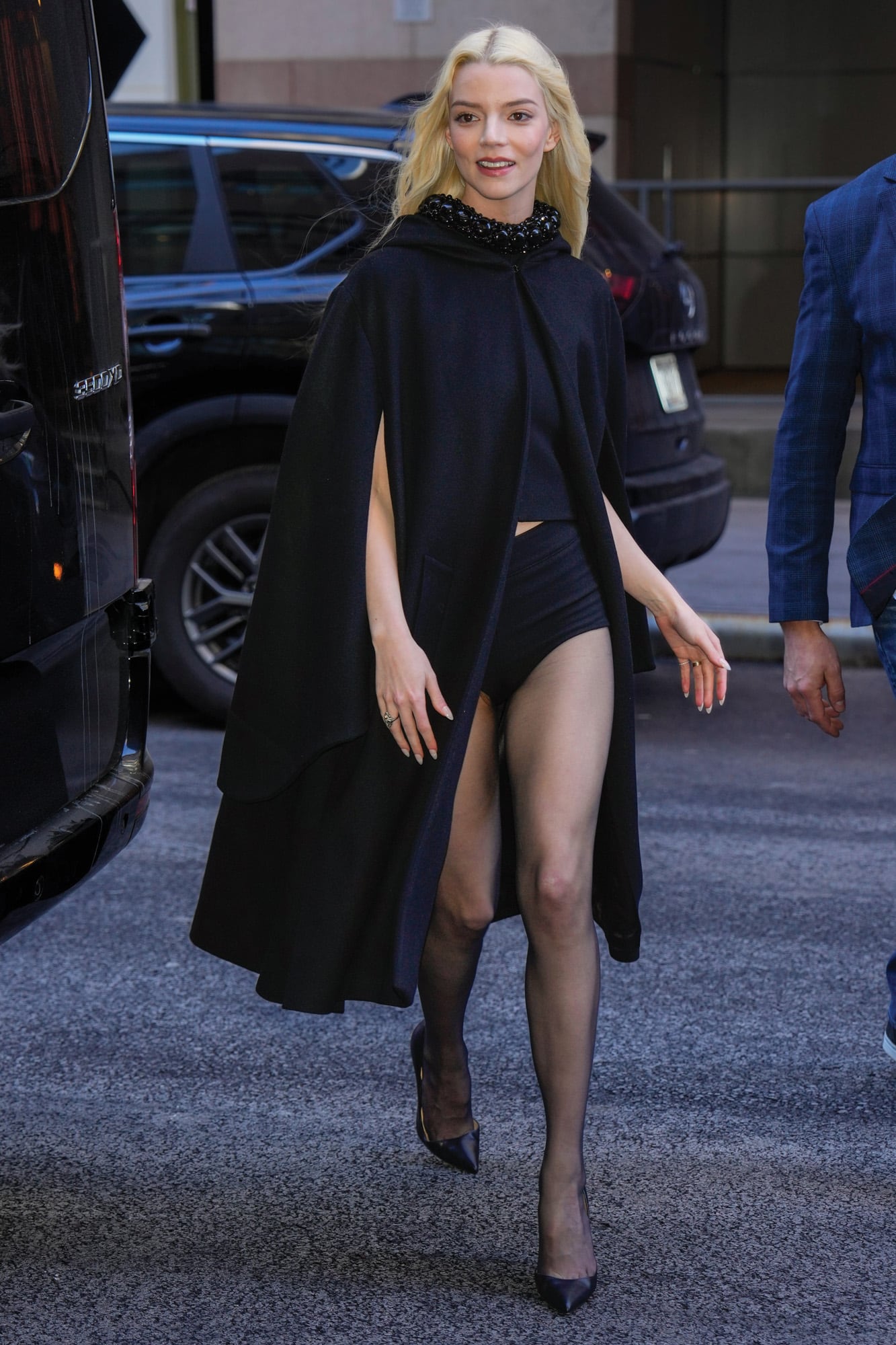 Un toque sensual en total black: crop top con pedrería y cuello alto, culotte y stilettos de Christian Louboutin bajo una de las prendas tendencia de este año: la capa.