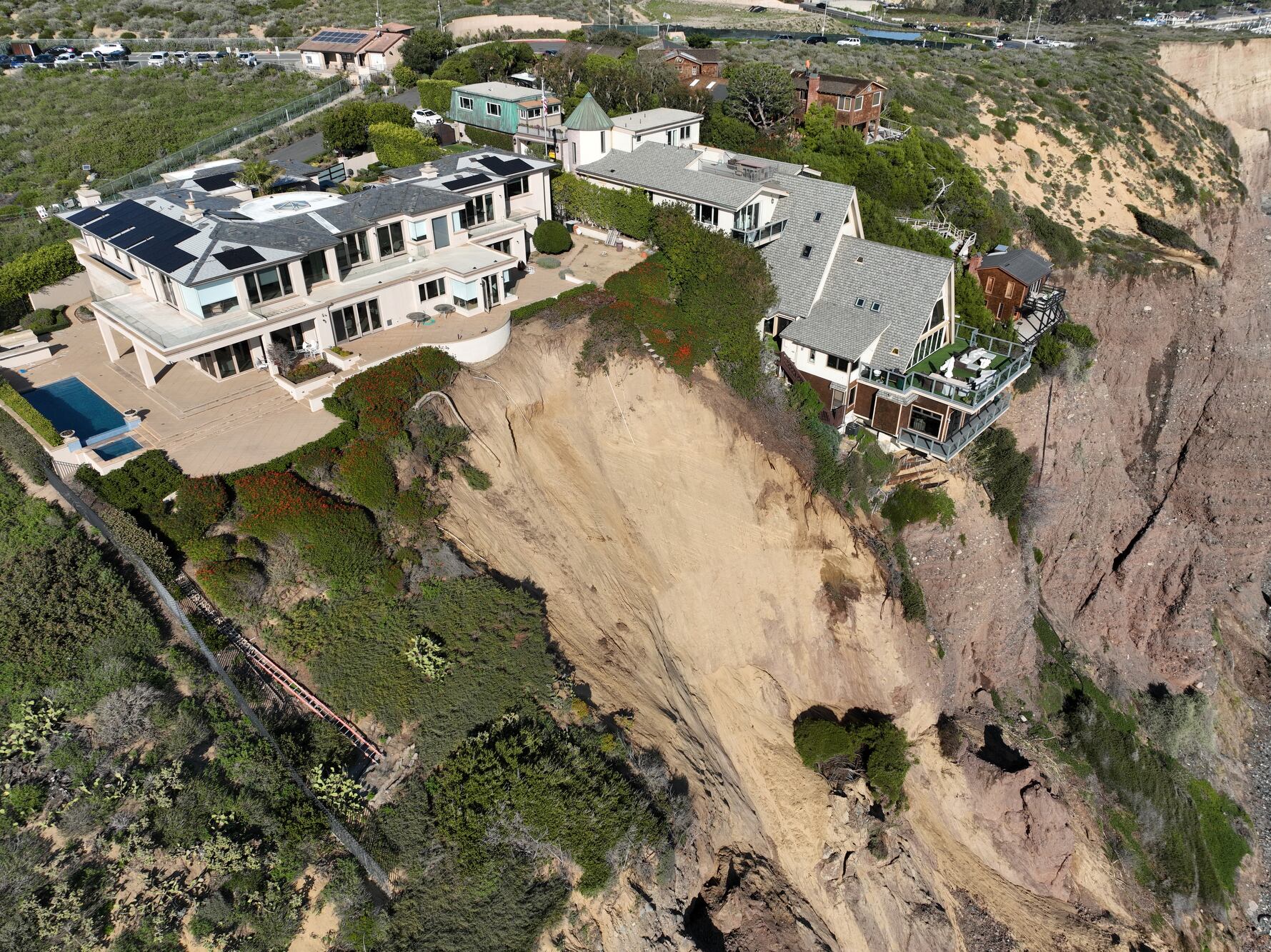 Vista aérea de tres casas grandes en Dana Point están en peligro de caer al océano después de que un acantilado cedió durante el fin de semana después de las fuertes lluvias recientes.