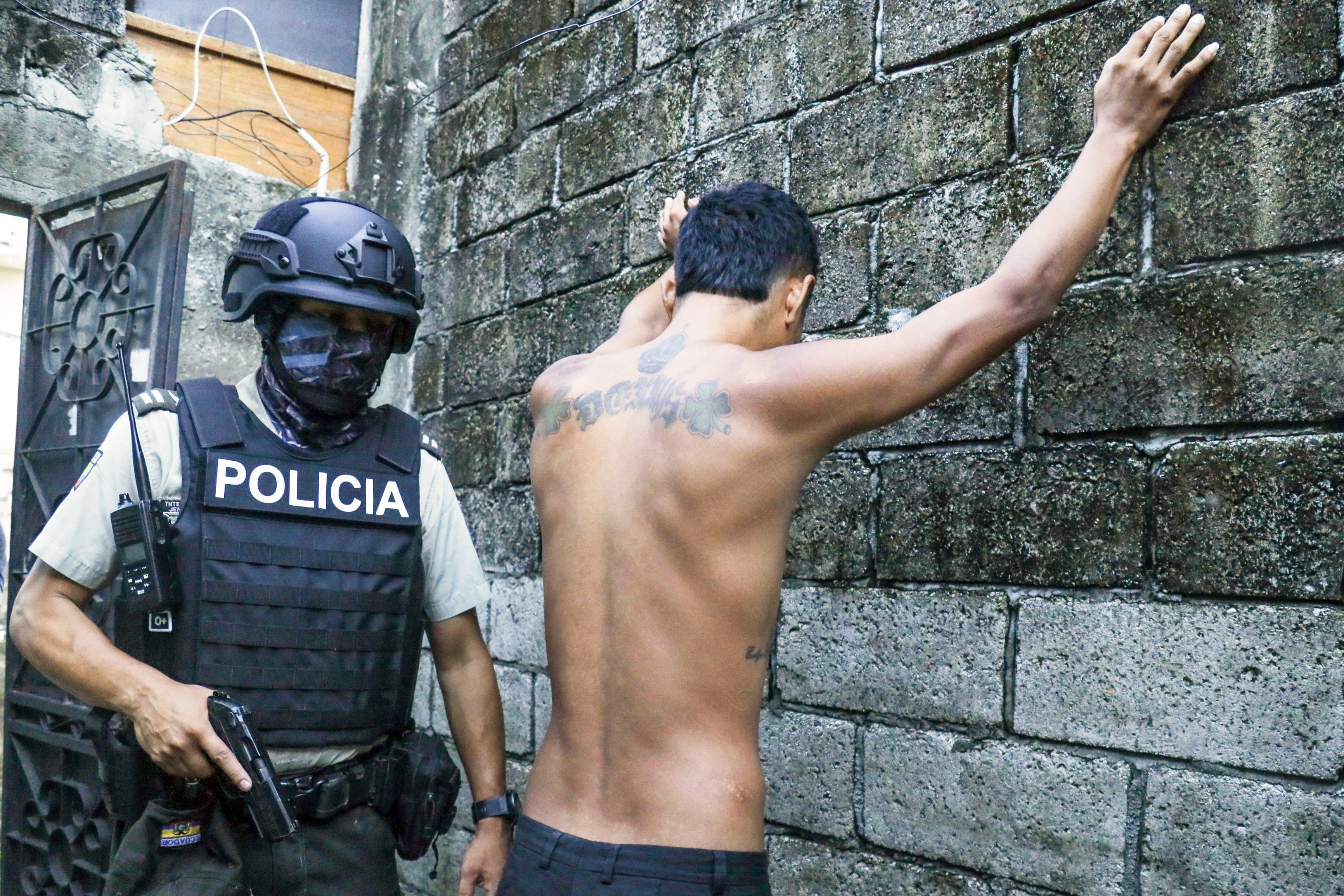 Un residente apoya las manos en un muro mientras la policía le registra para buscar armas o drogas, dentro de una operación contra grupos criminales en Guayaquil, Ecuador, el 4 de abril de 2024