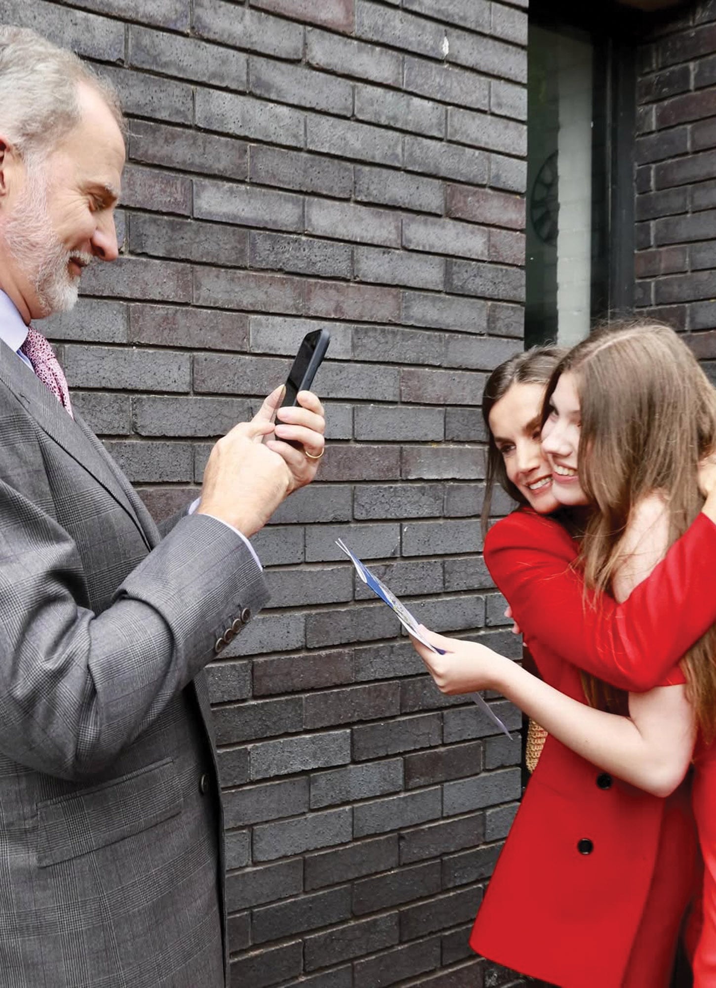 Felipe captura el momento con su celular mientras Letizia saluda cariñosamente a su hija menor.